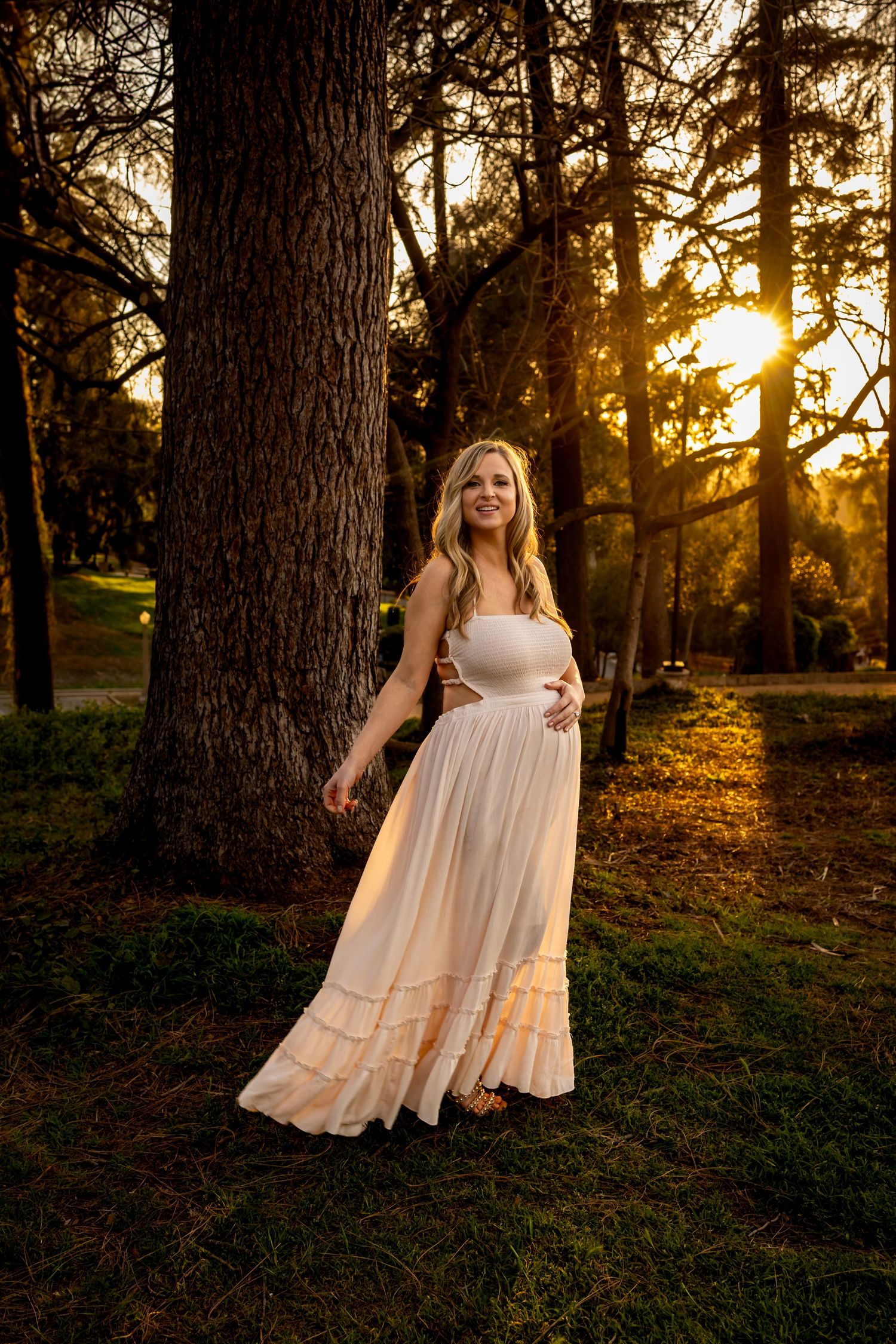 A sunset photoshoot among tall trees featuring a flowing white dress.