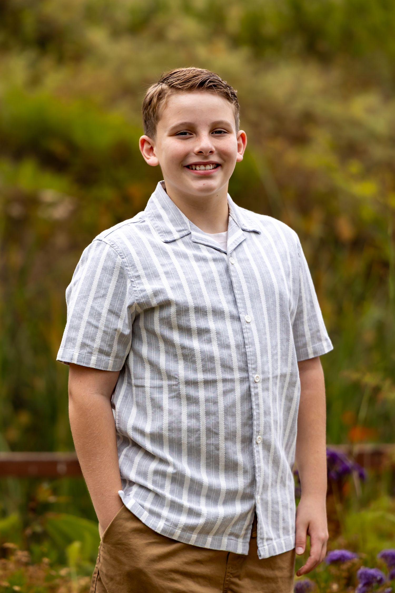 Candid portraits of young boy in striped shirt outdoors.