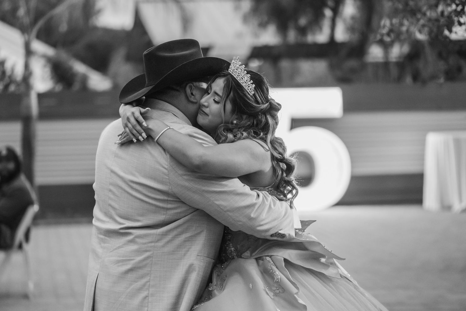 Black and white photo of an emotional embrace at a formal event with western attire.