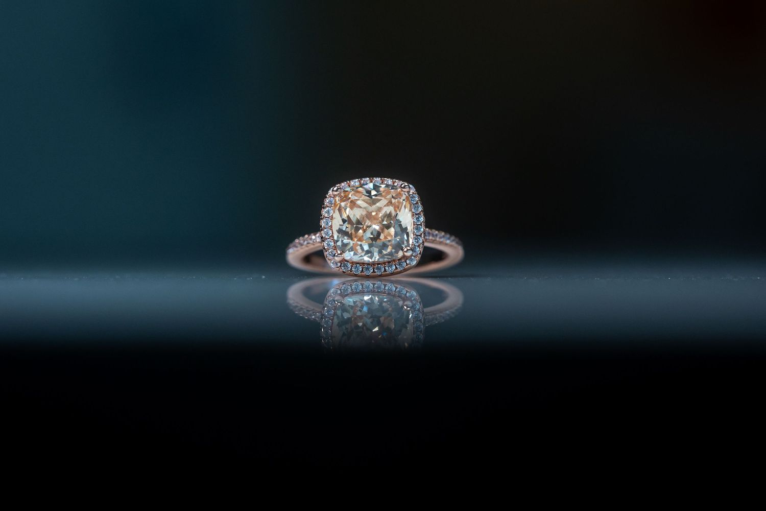Close-up shot of a sparkling diamond engagement ring on dark background.