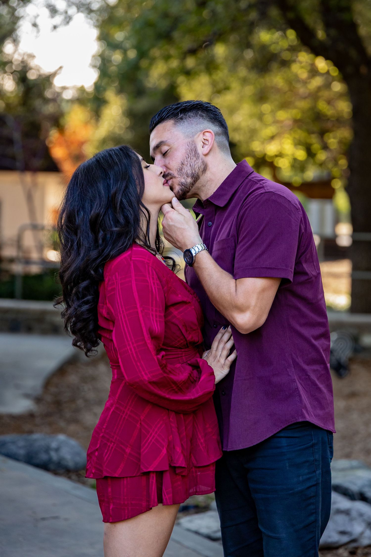 Romantic couple sharing an intimate moment outdoors, wearing coordinating red and purple outfits.