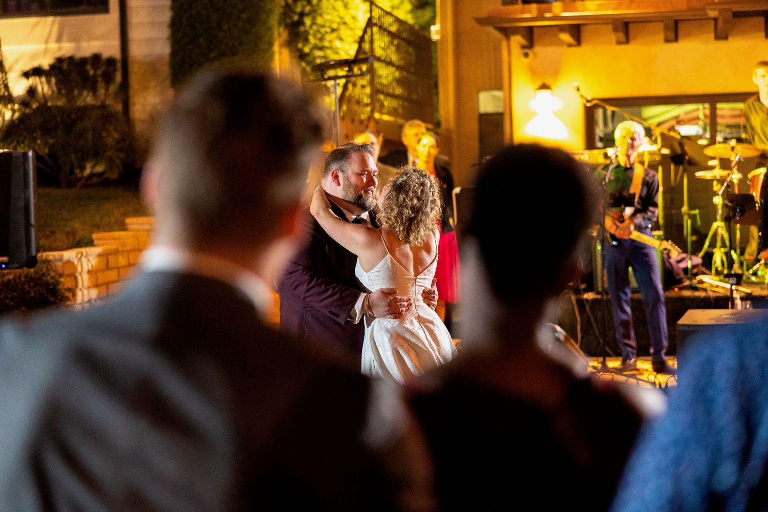 Wedding celebration in a warmly lit venue with guests watching the dance floor.