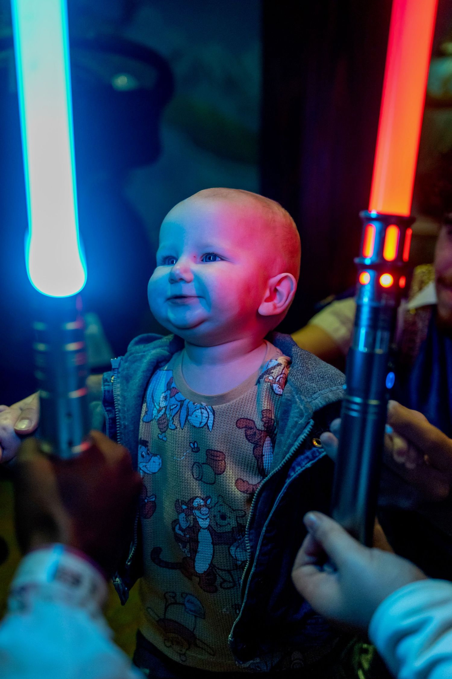 Baby smiles in colorful lighting with blue and red glowing effects.