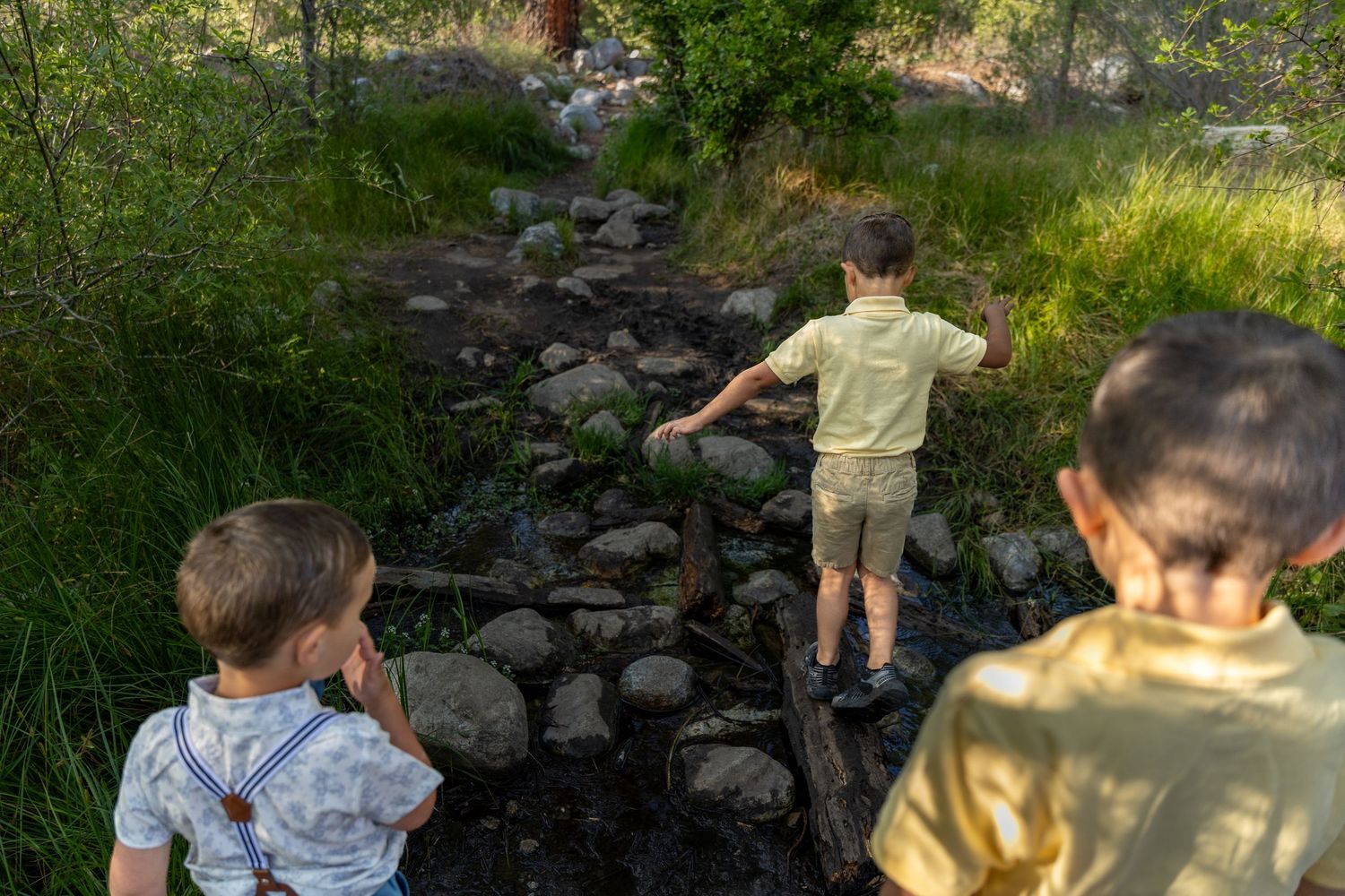 Children explore a rocky natural outdoor setting during a photoshoot.