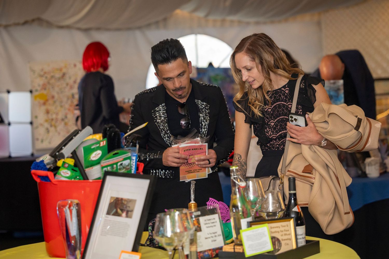 People gathered around table with supplies at casual indoor event.
