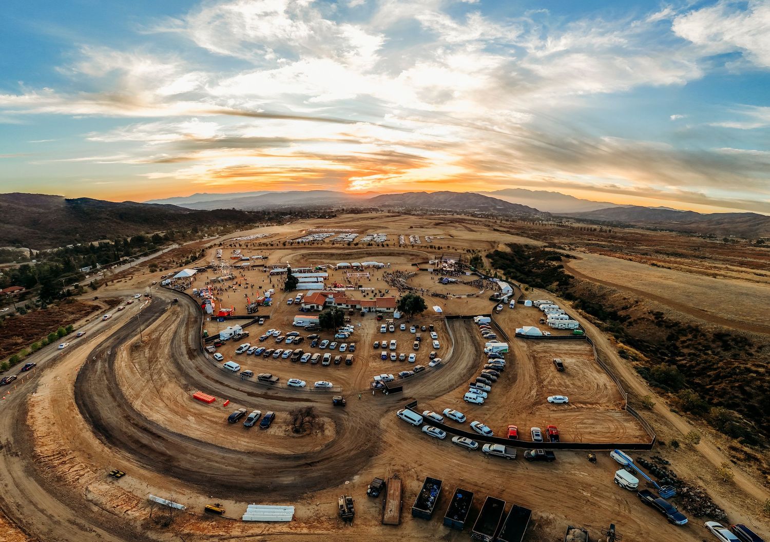 Aerial view of a desert campground with RVs arranged in a circular pattern during sunset.