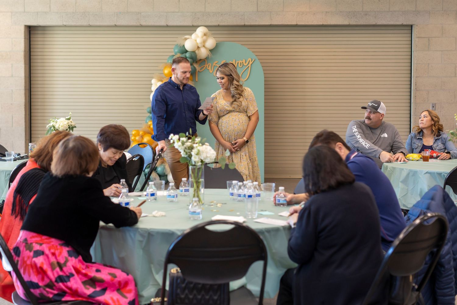 Wide shot of guests seated at tables during a baby shower celebration.