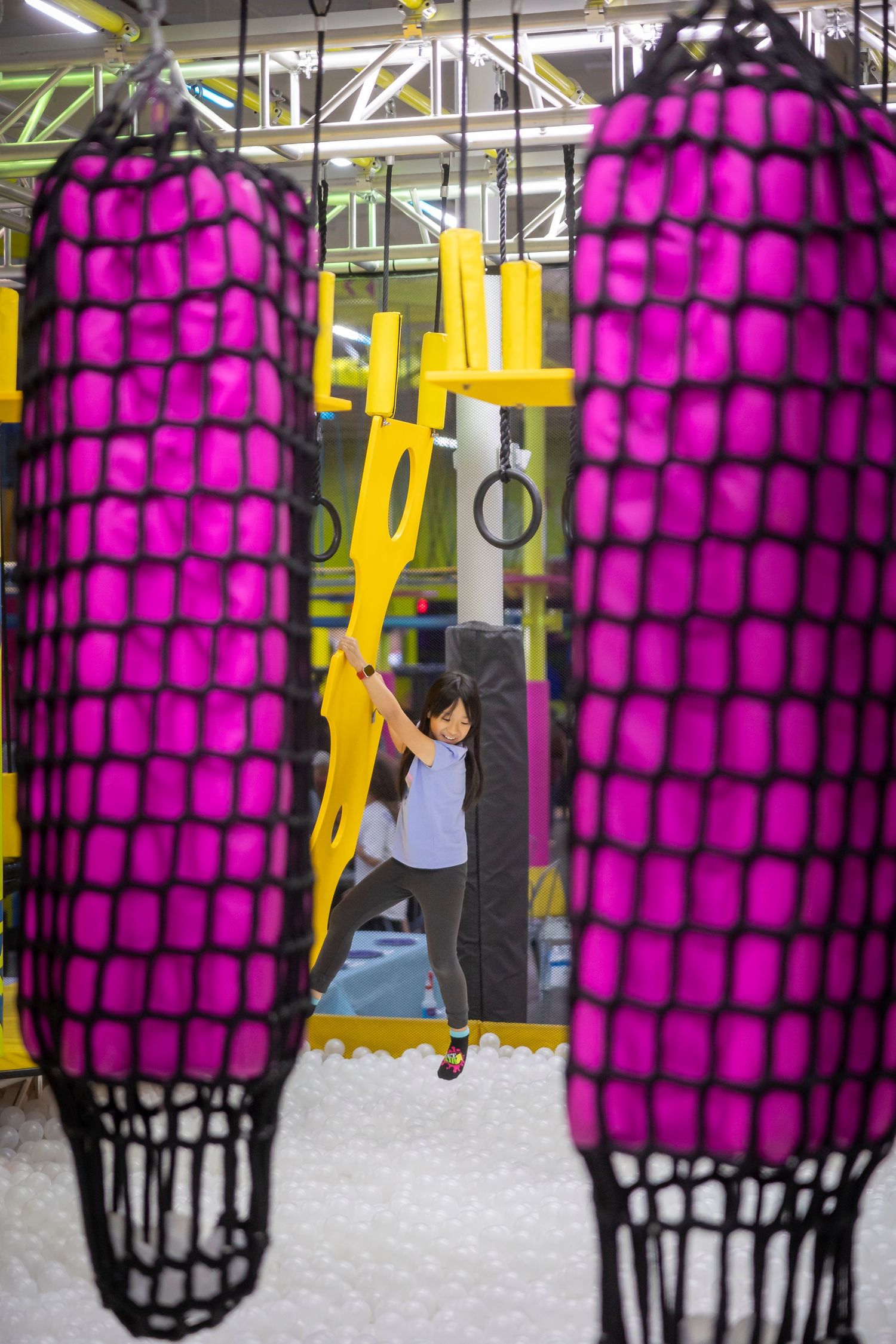 Pink and black geometric climbing structures in an indoor recreation facility.