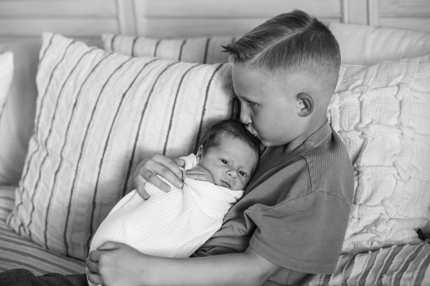 Two siblings bonding and cuddling on striped bedding in sweet progression of images.