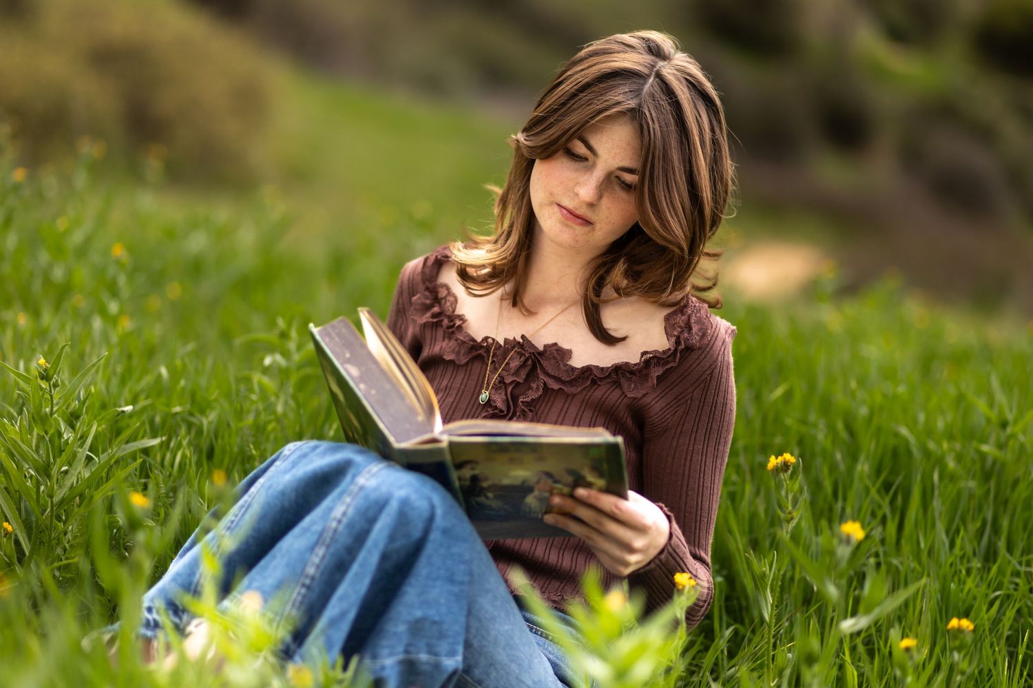Reading a book while sitting in green grass during golden hour in Redlands.
