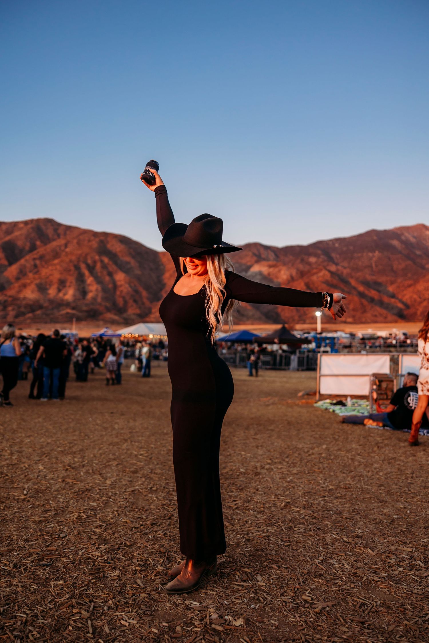 A silhouette stands with arms outstretched against mountain backdrop at dusk.