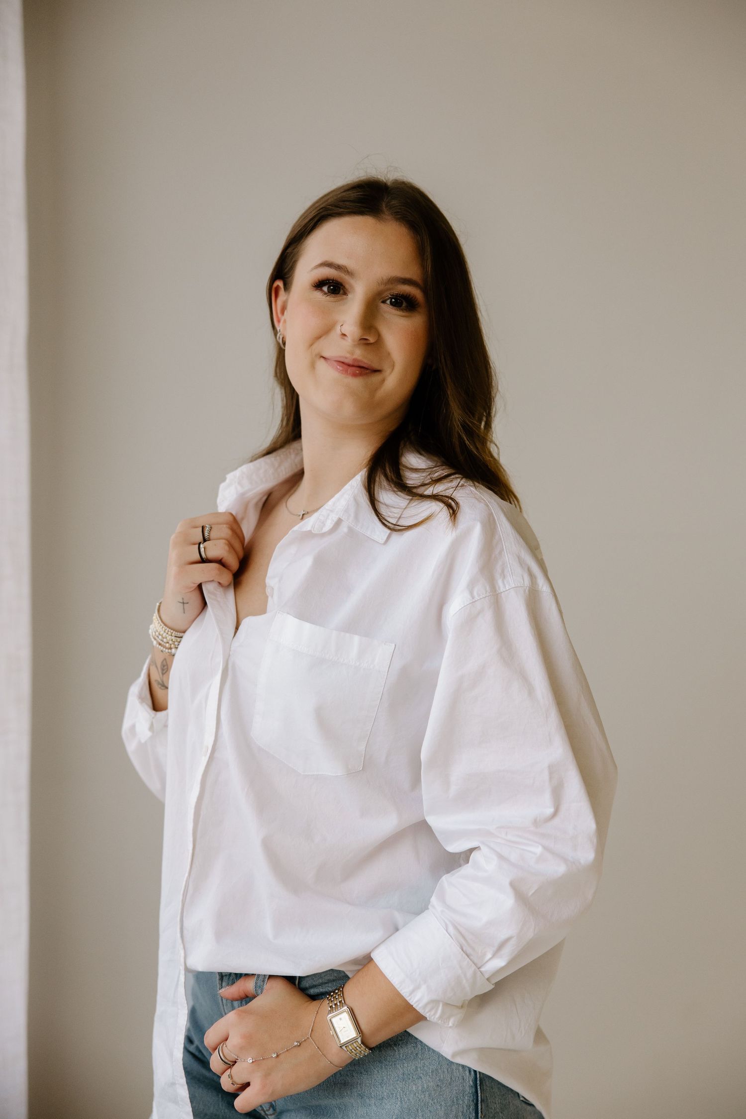 Studio portrait of a woman in a classic white button-down shirt against a neutral background.
