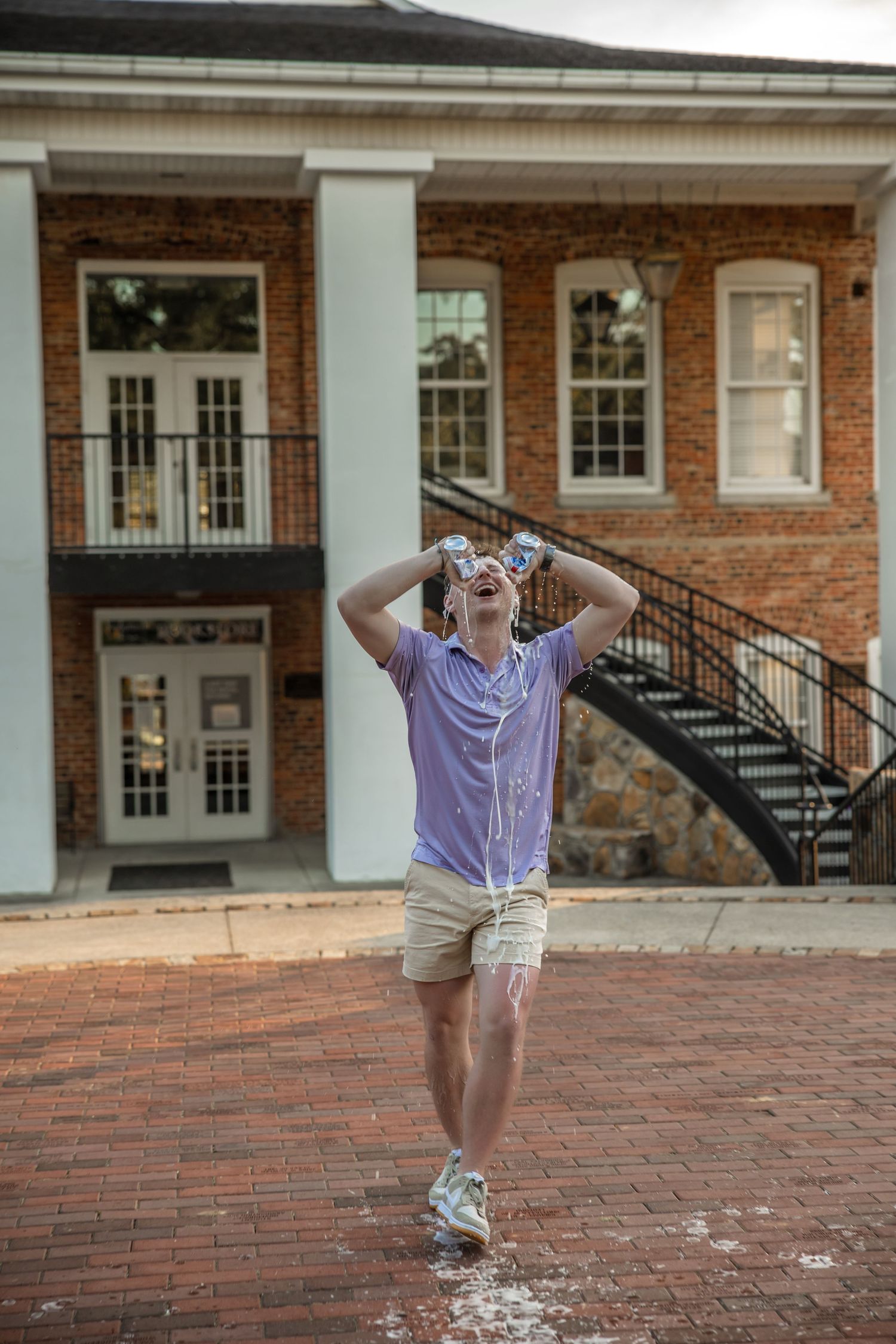 Graduate celebrates joyfully in front of brick academic building with white columns.