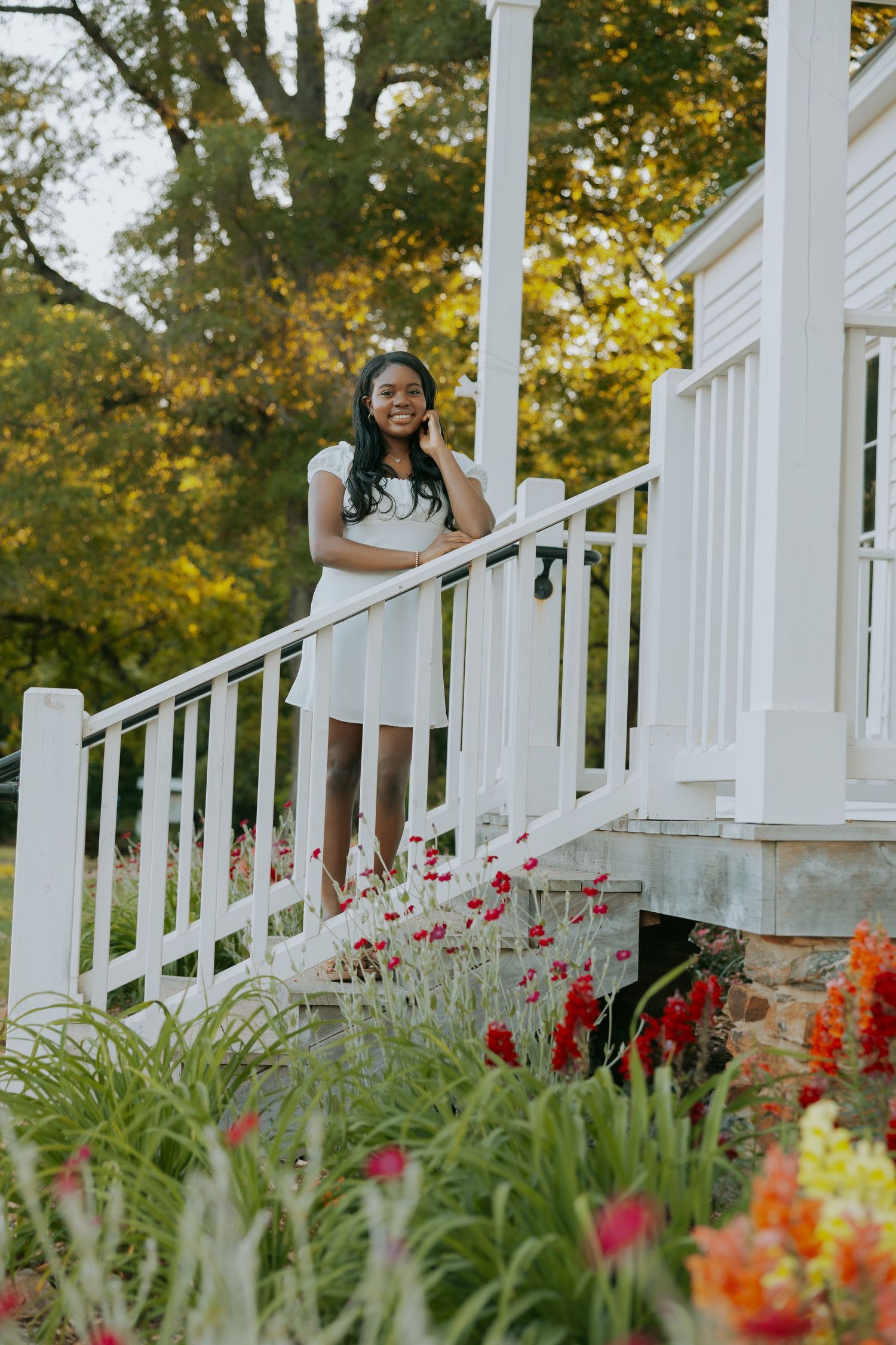 A white dress stands on a porch railing surrounded by colorful tulips and garden flowers.