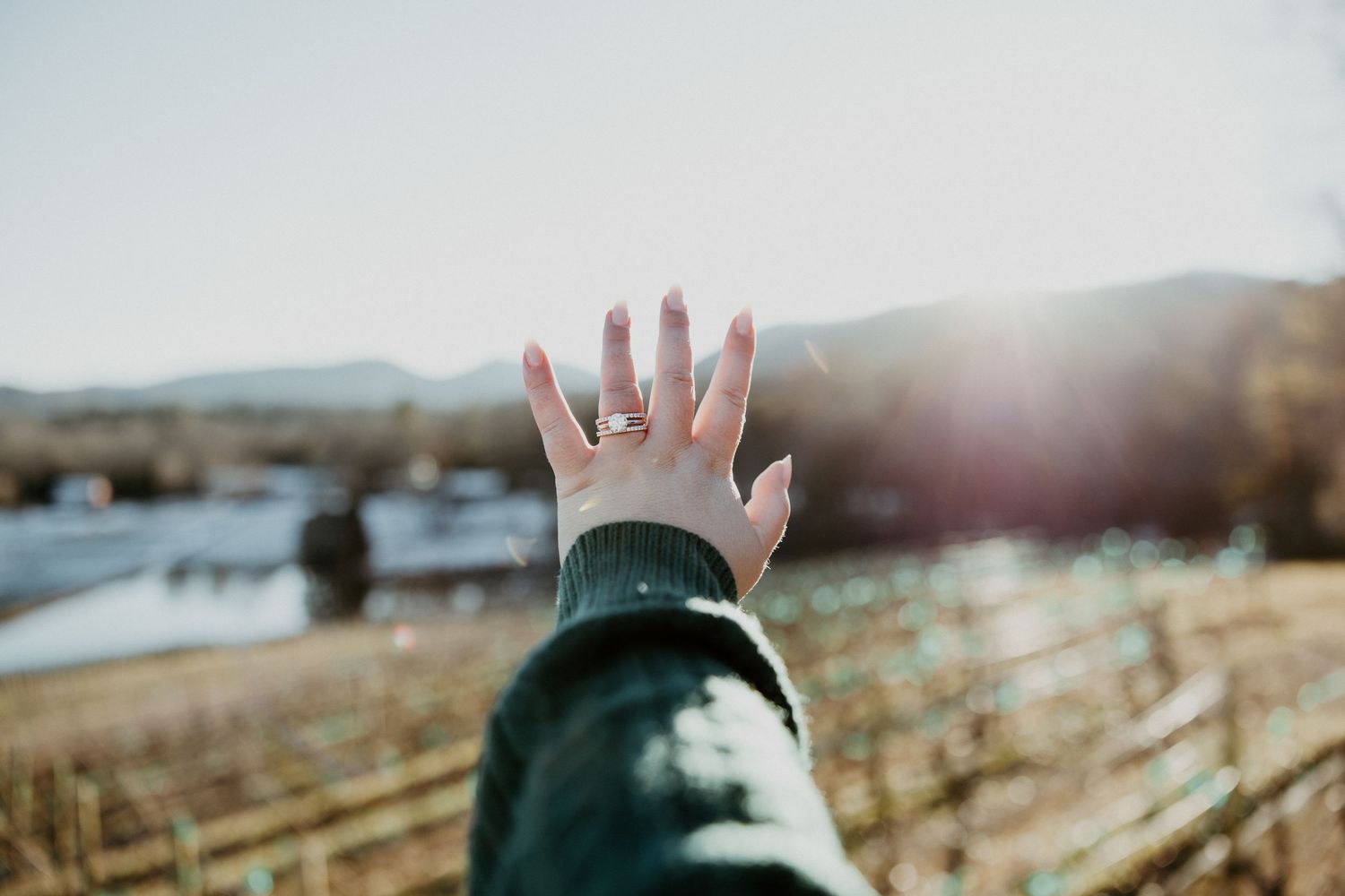Ring-adorned hands raised against a bright winter sky.
