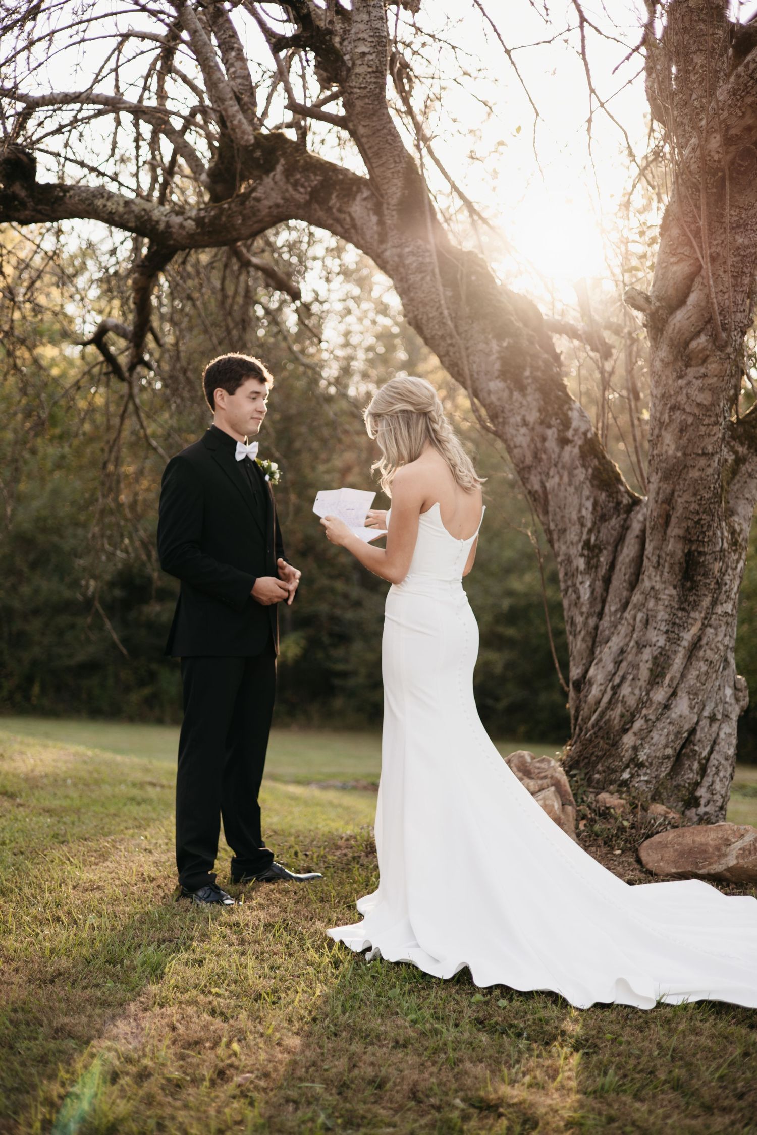 Sunset wedding ceremony with couple exchanging vows under old trees.