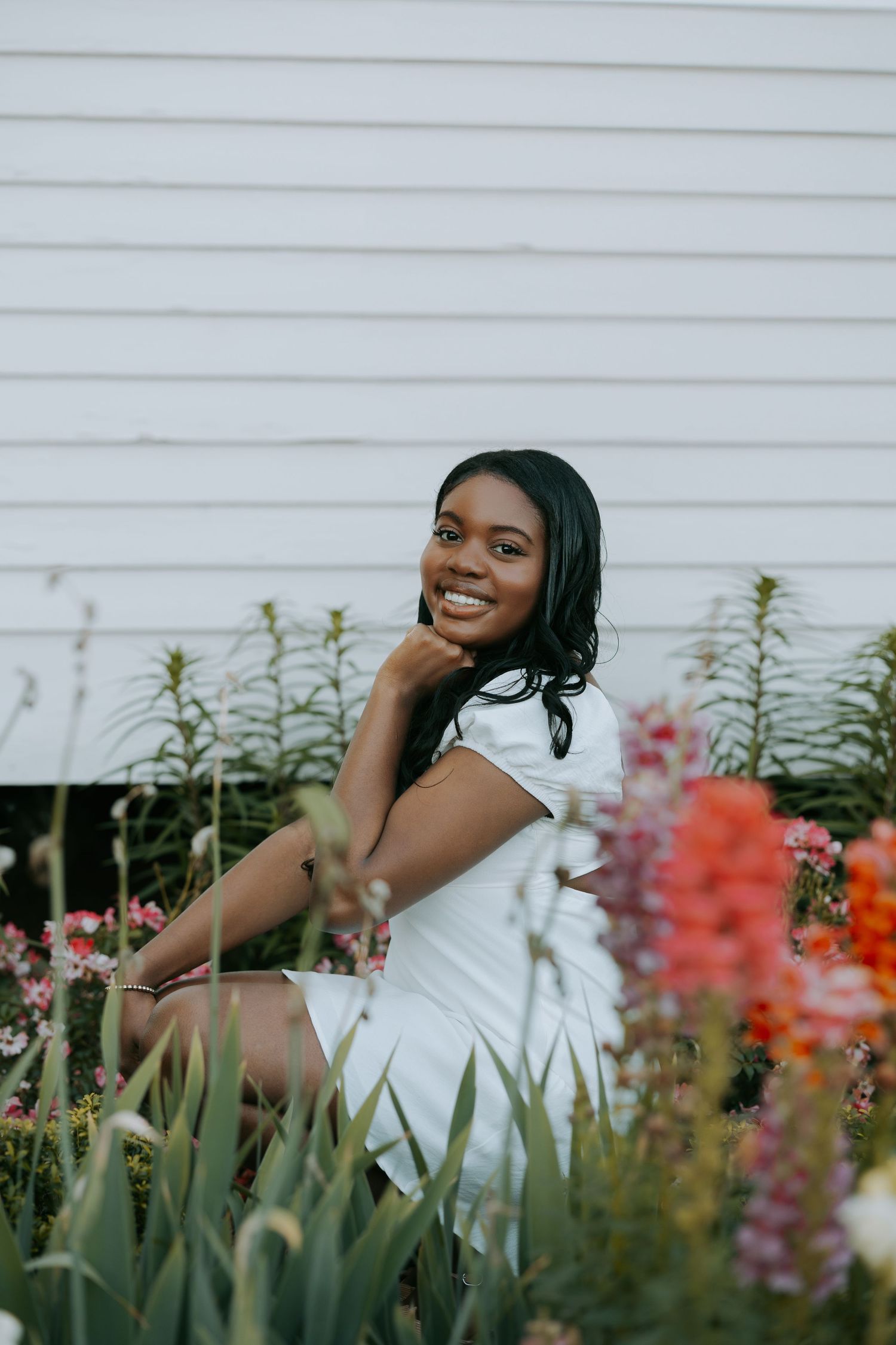 A series of joyful portraits in a garden with vibrant red and orange flowers against a white wall backdrop.