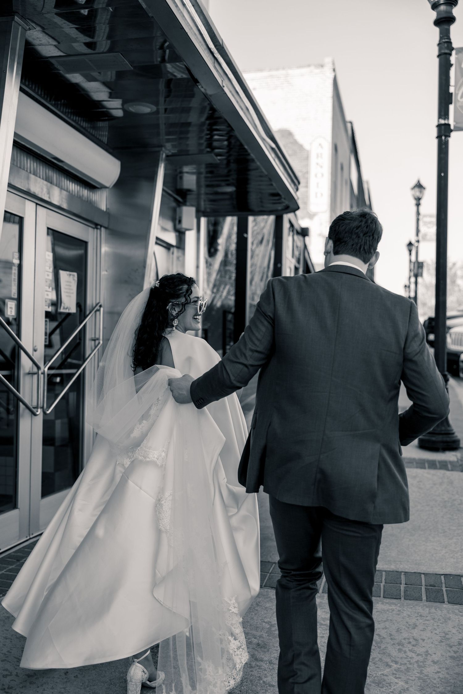 Wedding party walks down a vintage cobblestone street in black and white formal attire.