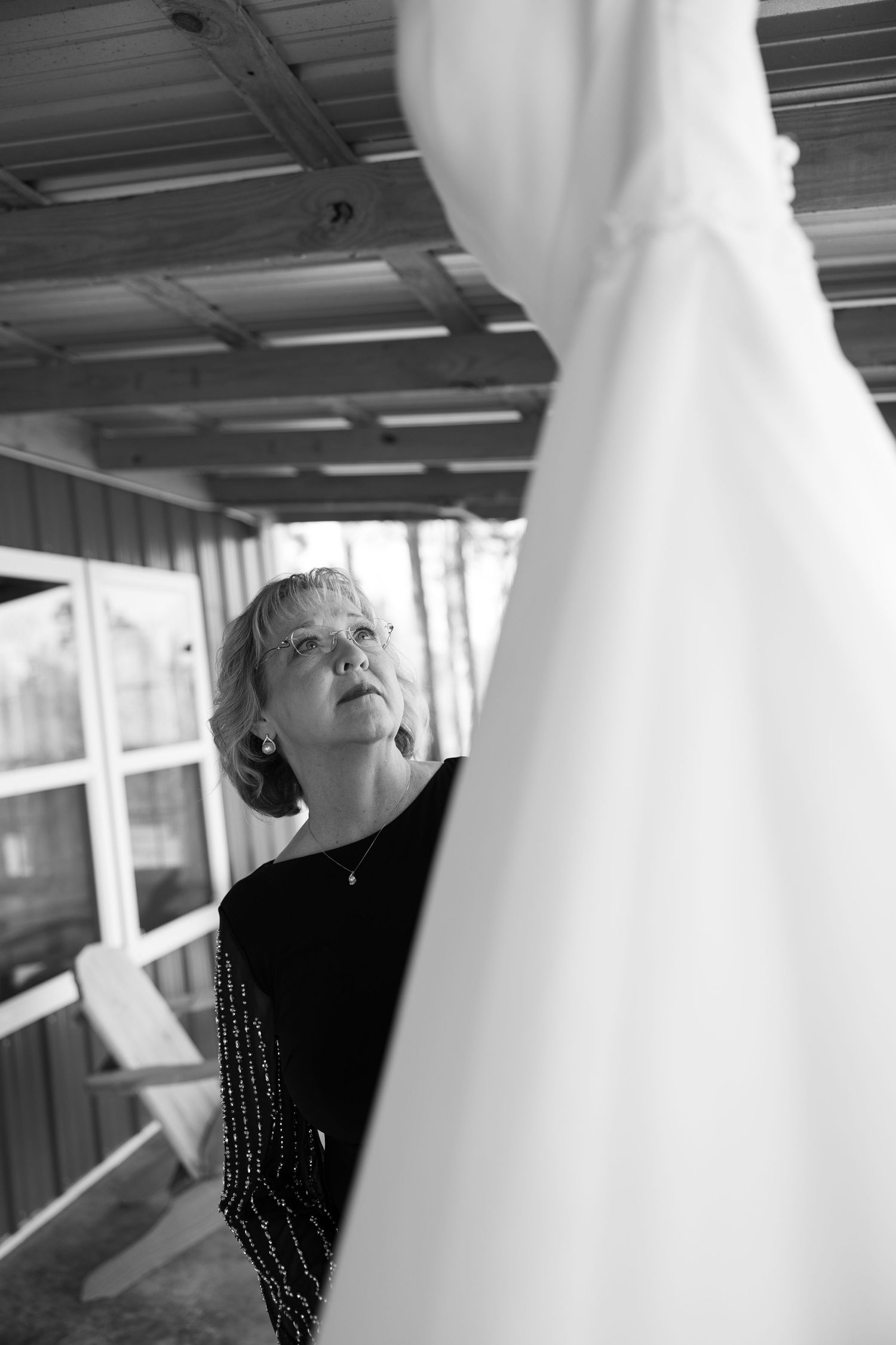 Black and white image of wedding dress detail with dramatic lighting.