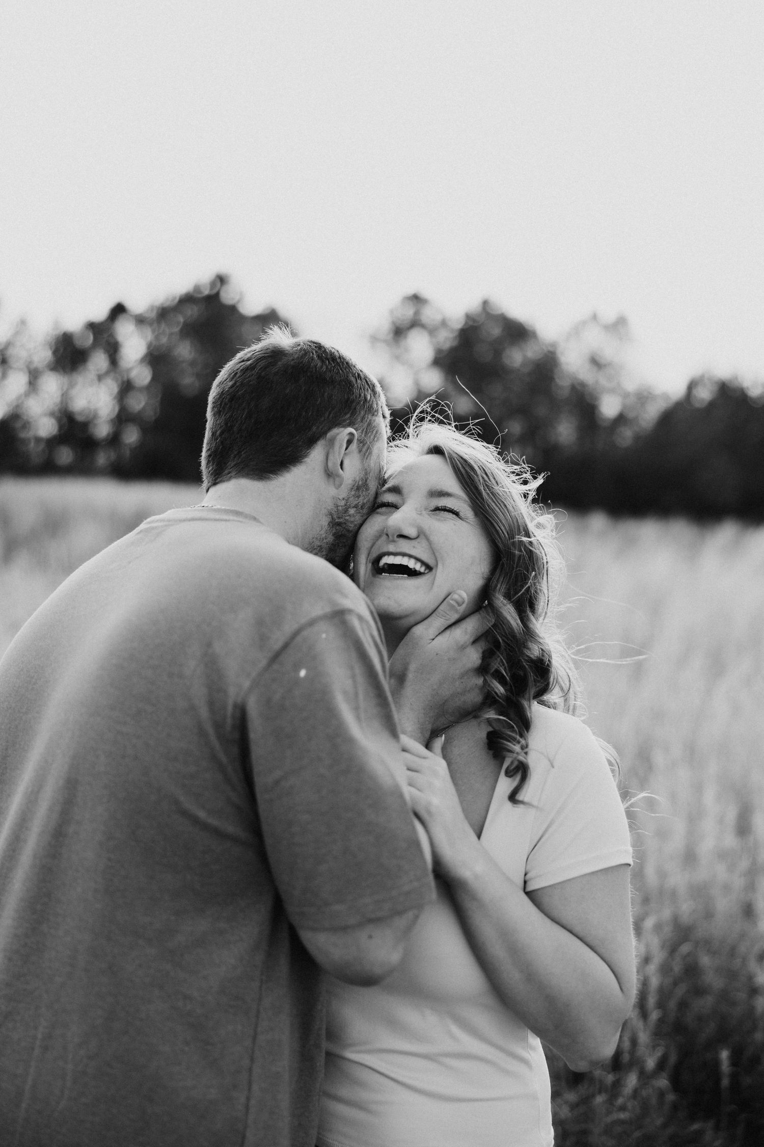 A joyful moment captured between a couple in a sunlit field.