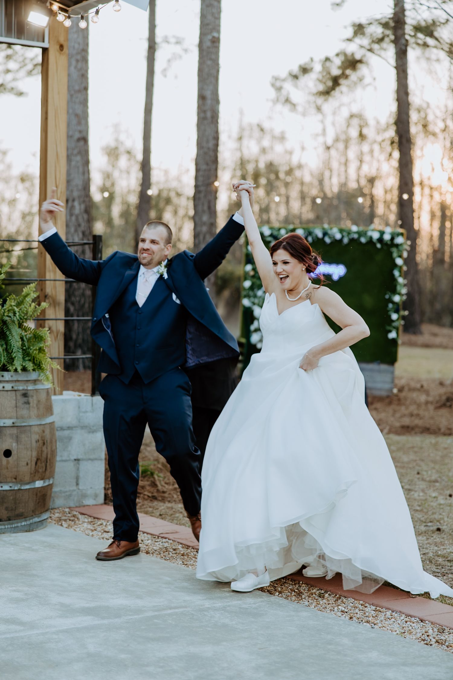 A joyful couple celebrates during their outdoor wedding ceremony on a rustic patio with trees in the background.