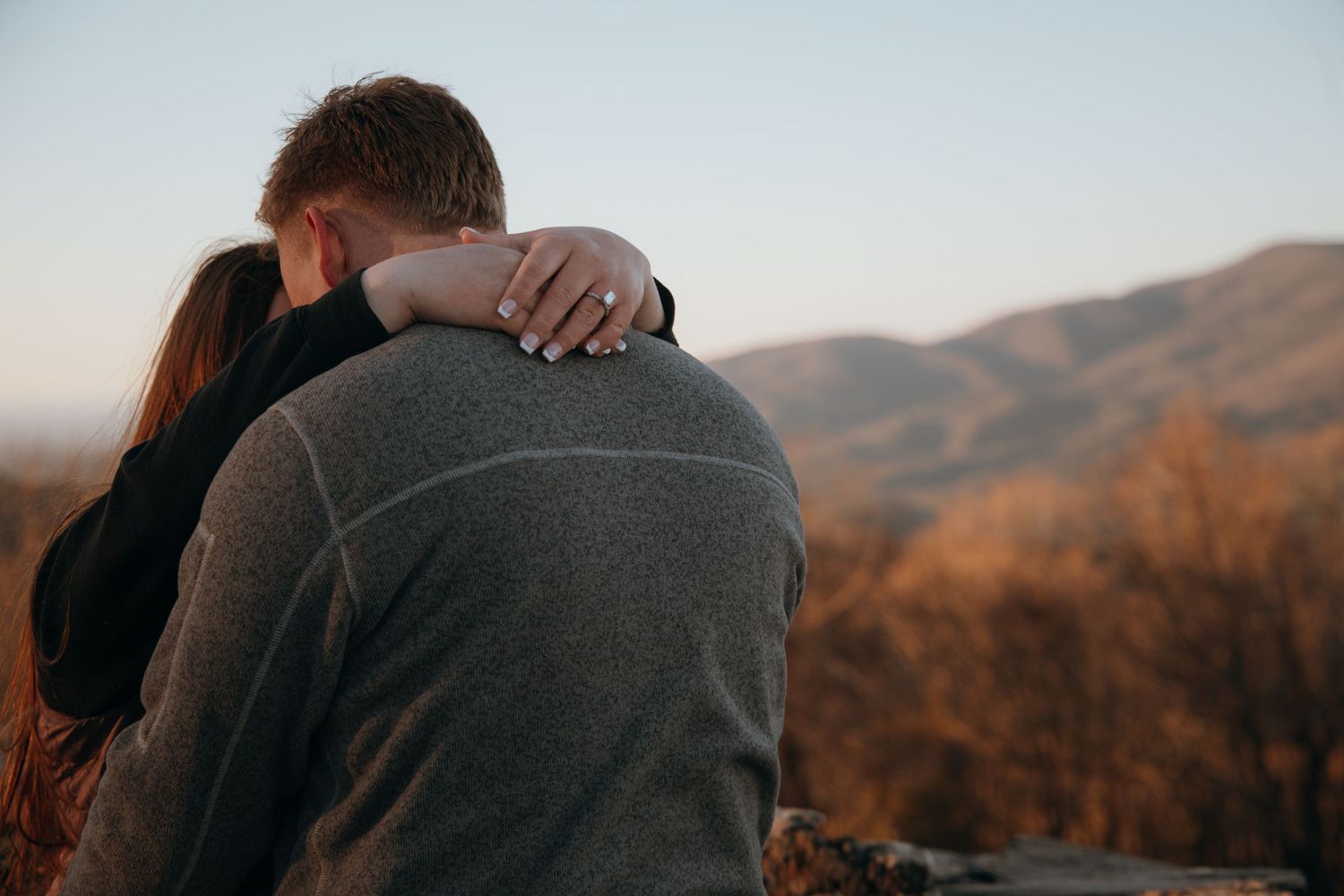 Silhouettes embracing against a mountain backdrop at sunset.
