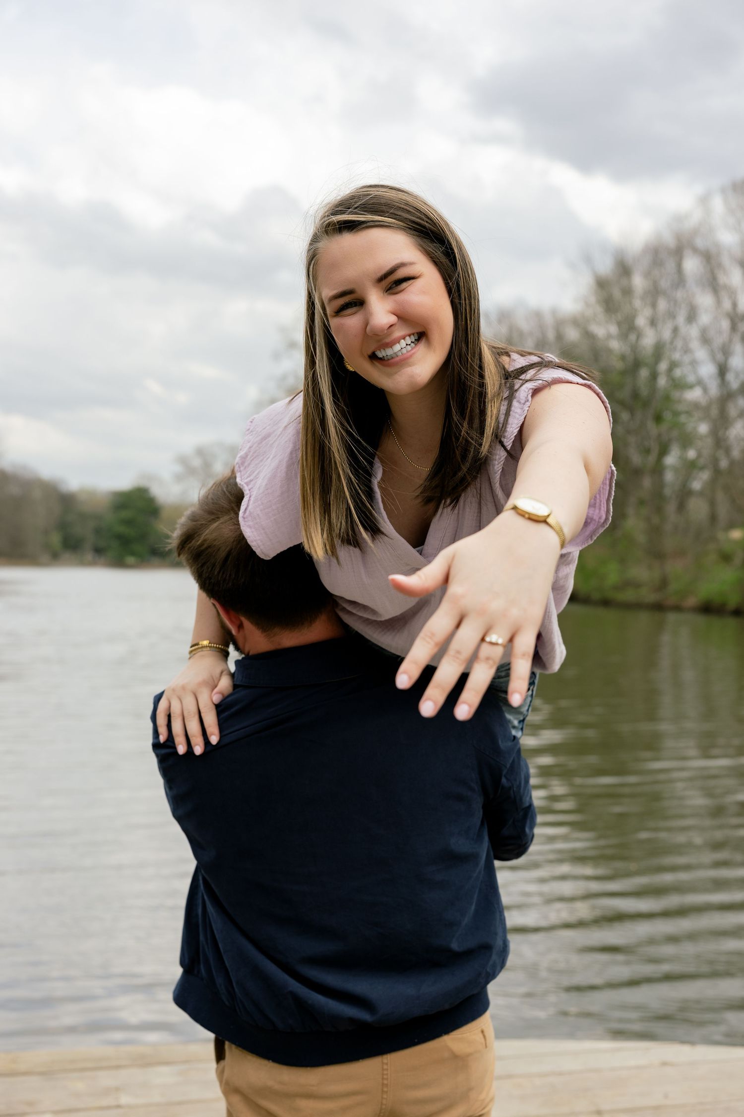 A joyful couple shares a playful moment on a dock by a lake.