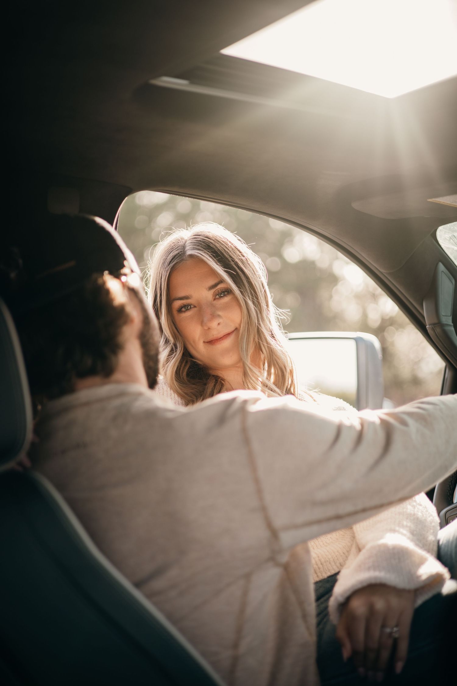 Candid moments captured between a couple inside a sunlit car.