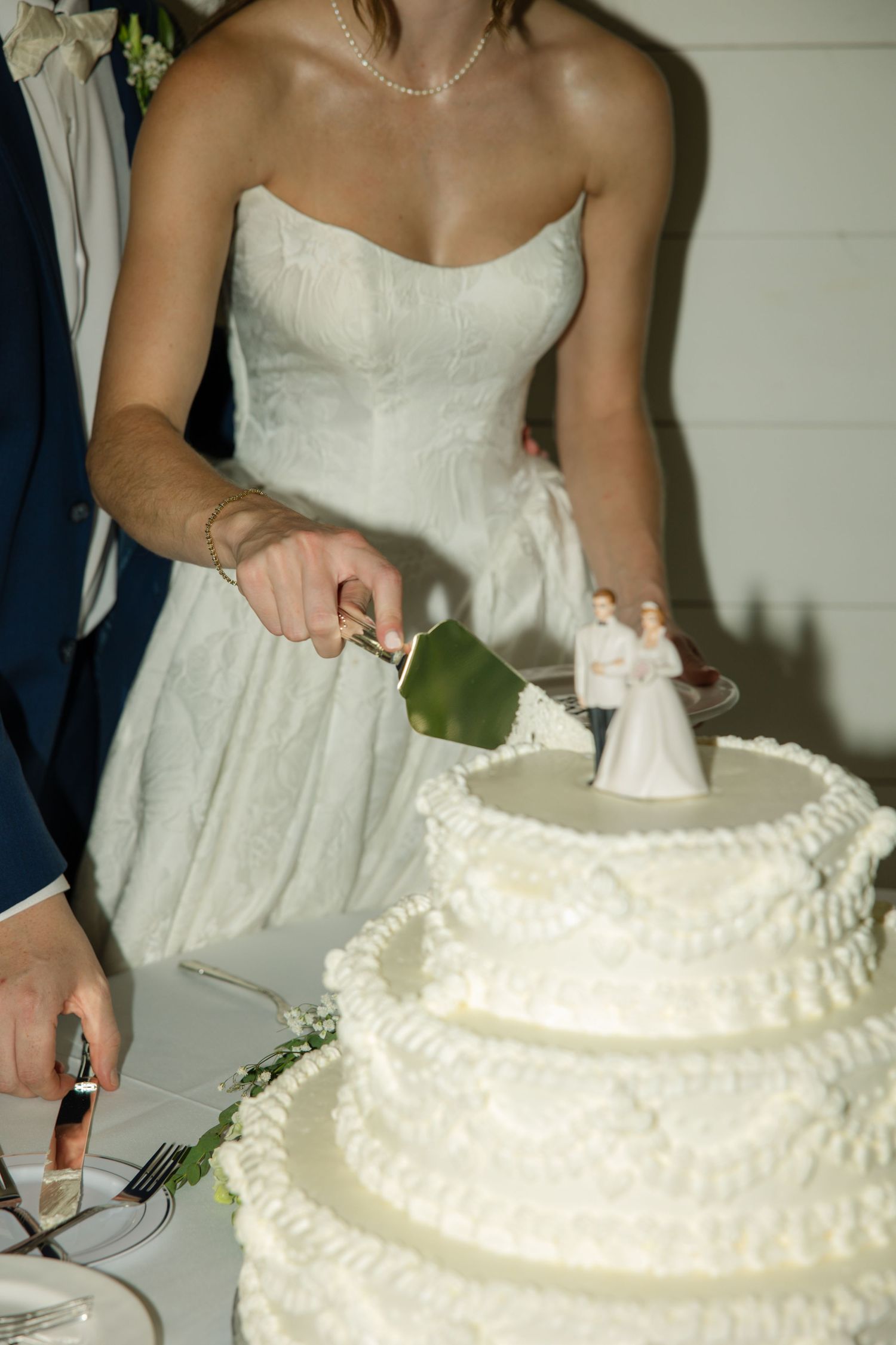 A sequence of photos showing someone in a white wedding dress cutting into a traditional tiered white wedding cake.