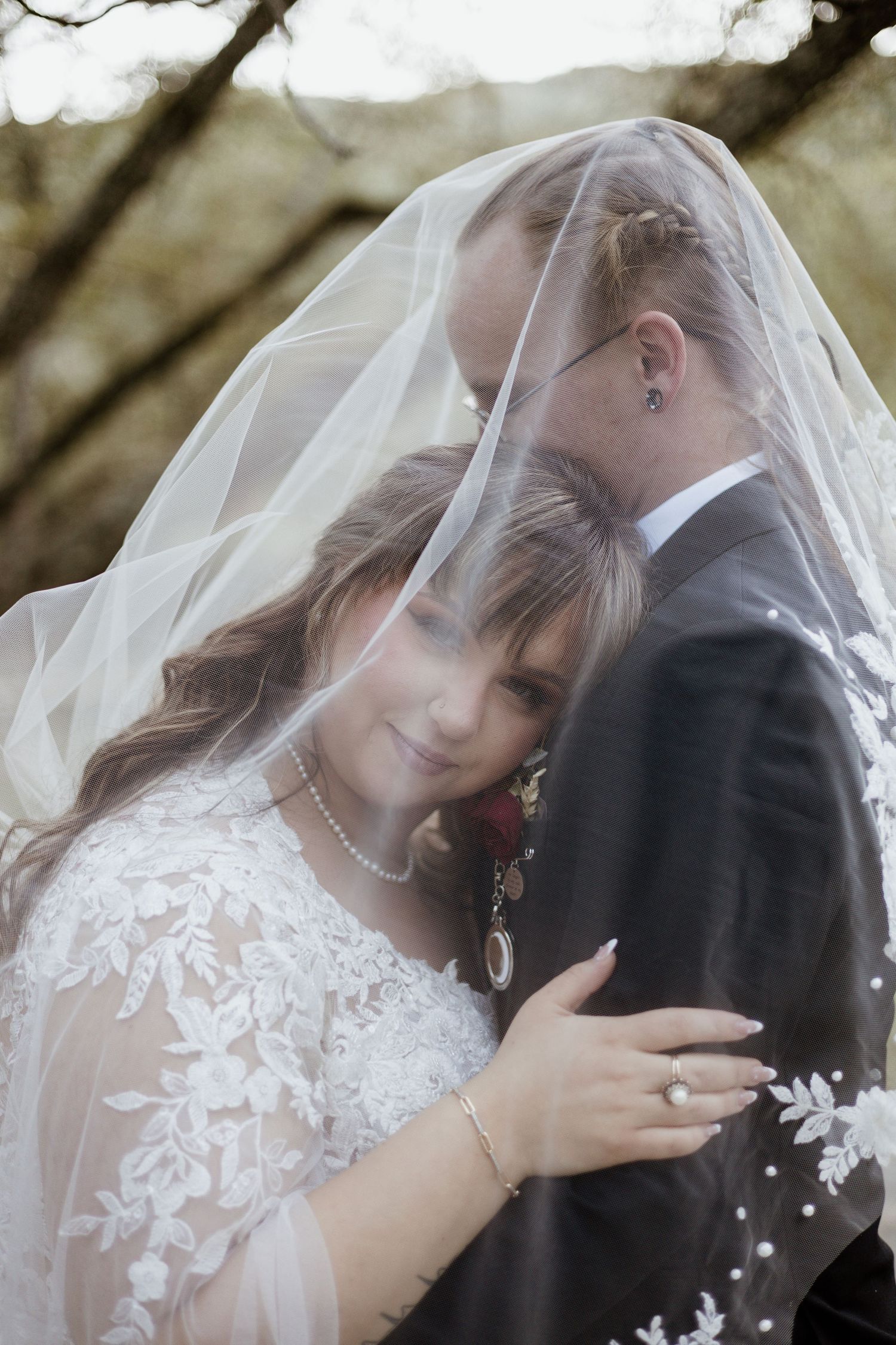 An intimate moment captured under a delicate white veil during a wedding photoshoot.