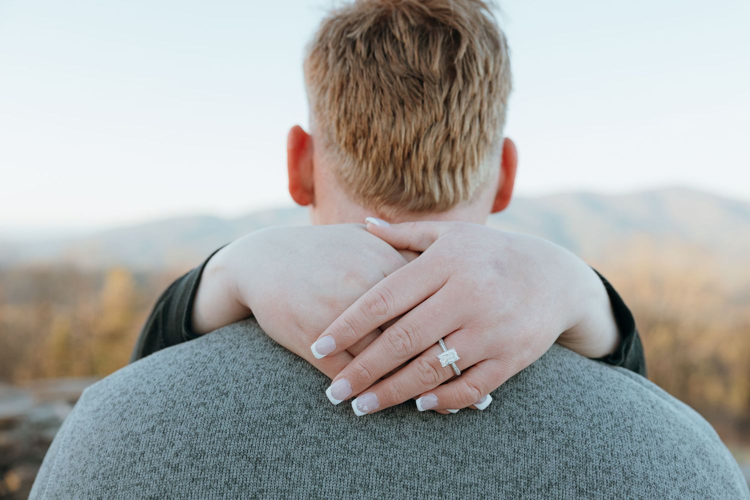 Hands gently resting on shoulders in soft natural light.