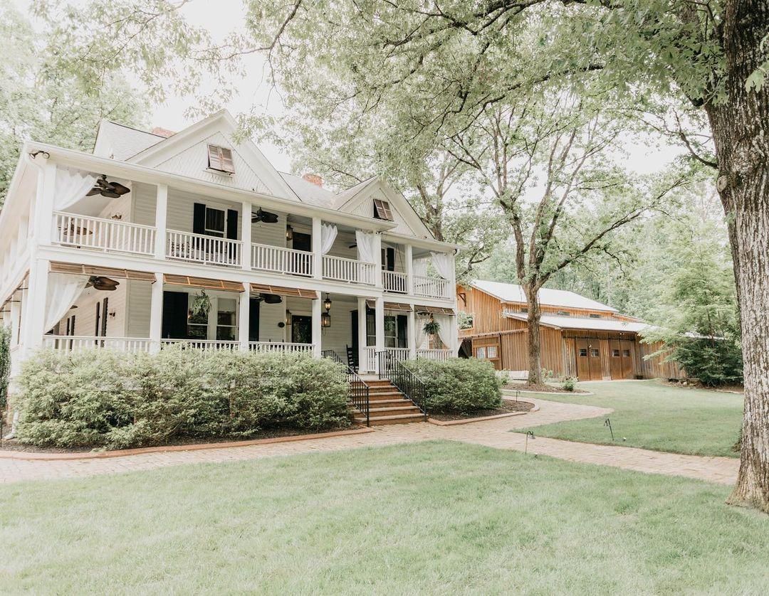 White suburban houses with porches set on green lawns surrounded by mature trees.