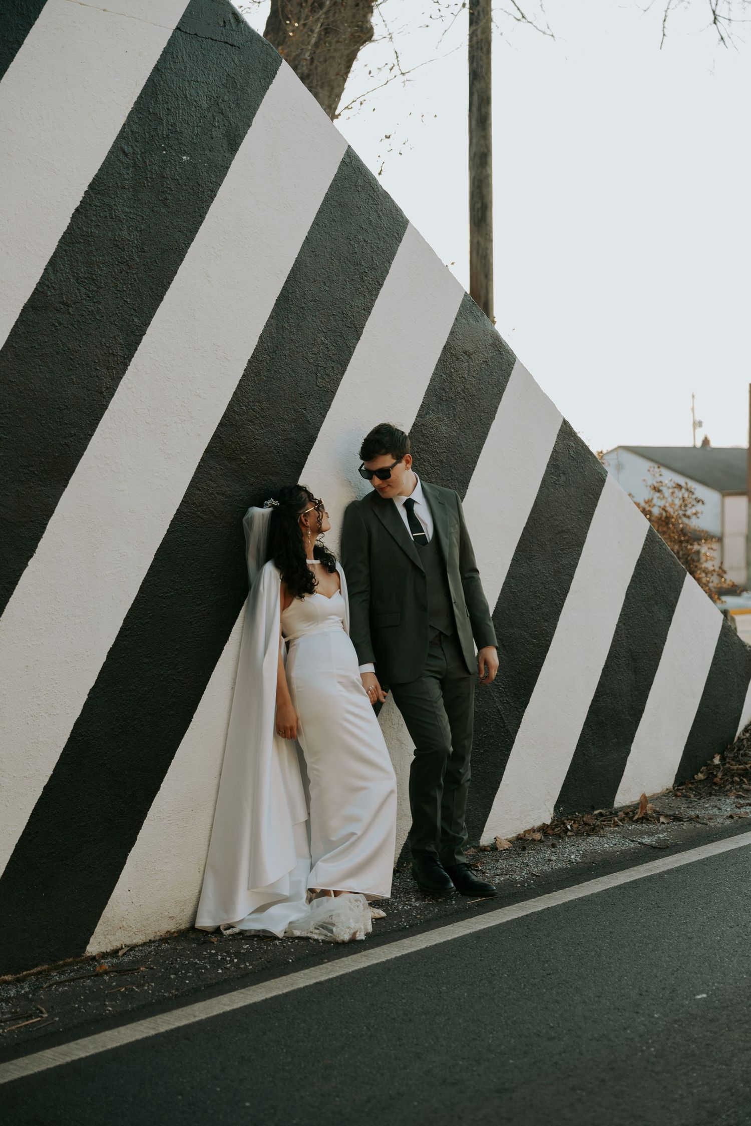 A couple in wedding attire poses against a dramatic black and white striped wall in a creative photo sequence.