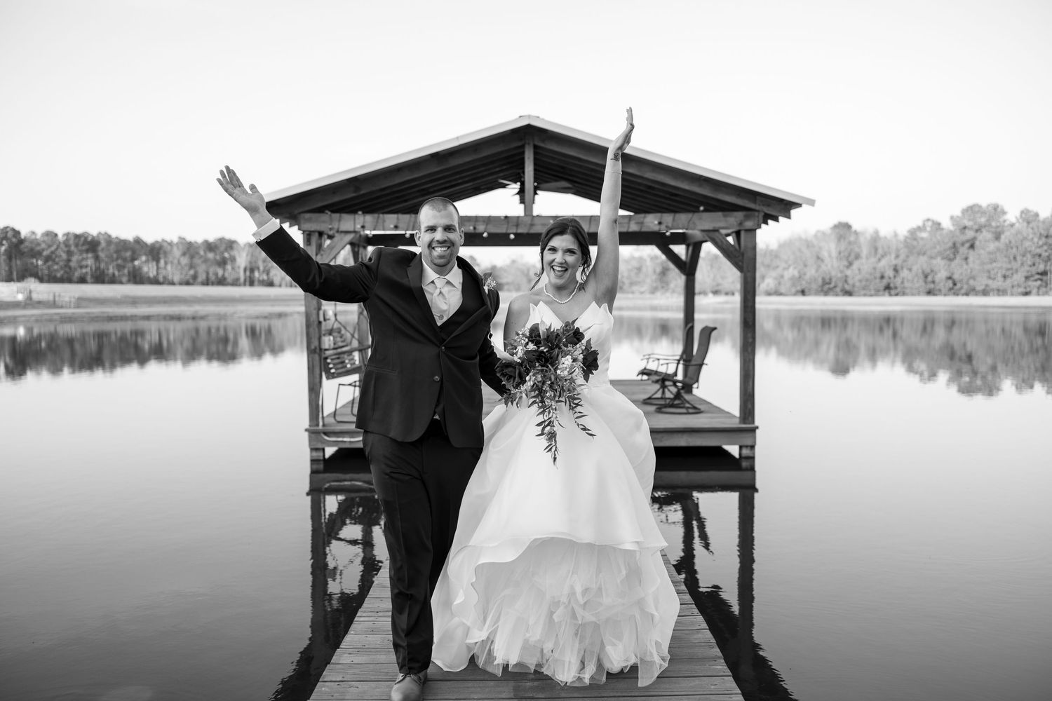A romantic moment captured on a wooden dock overlooking a calm lake.