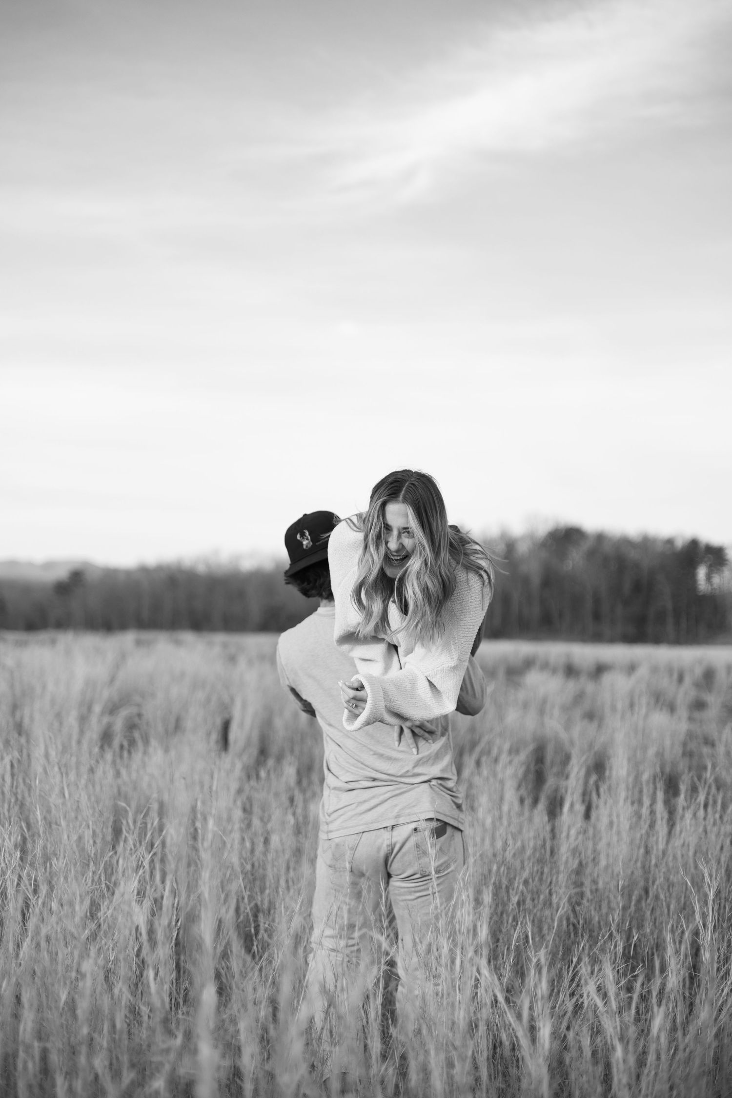 Black and white photos of someone dancing joyfully in a field of tall grass.