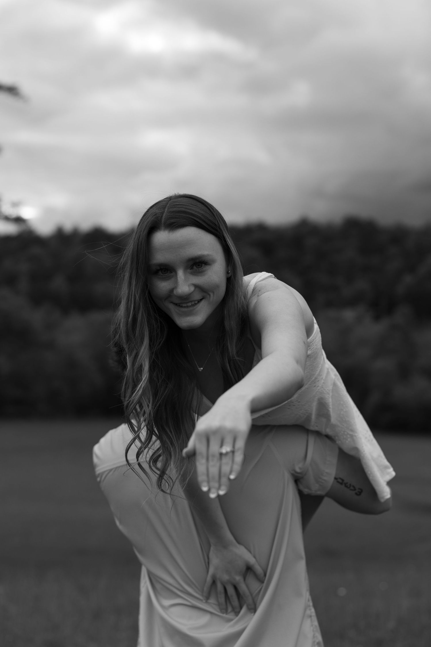 A black and white portrait showing a joyful pose in an outdoor setting.