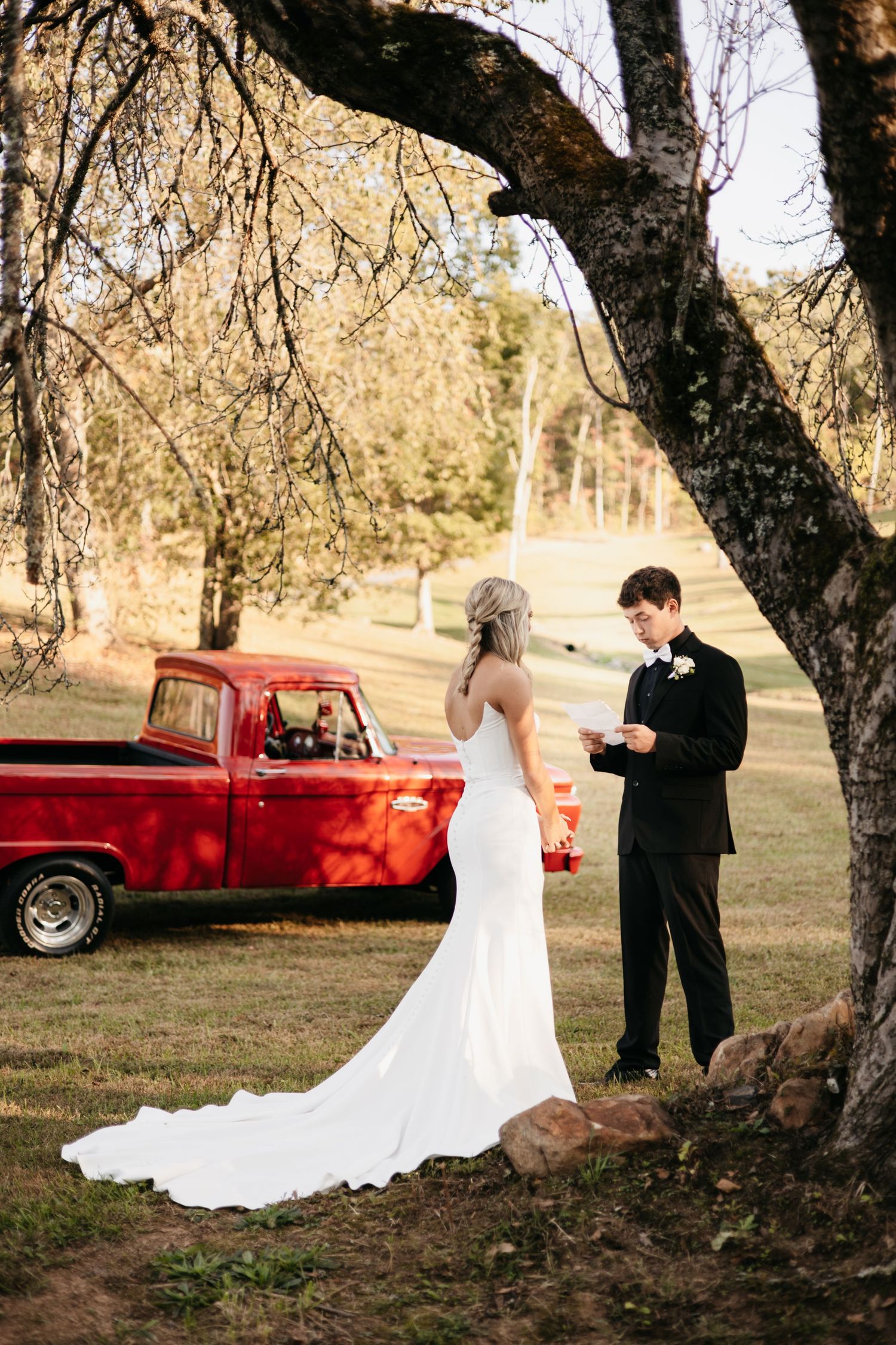 Wedding ceremony in autumn with vintage red truck in background.