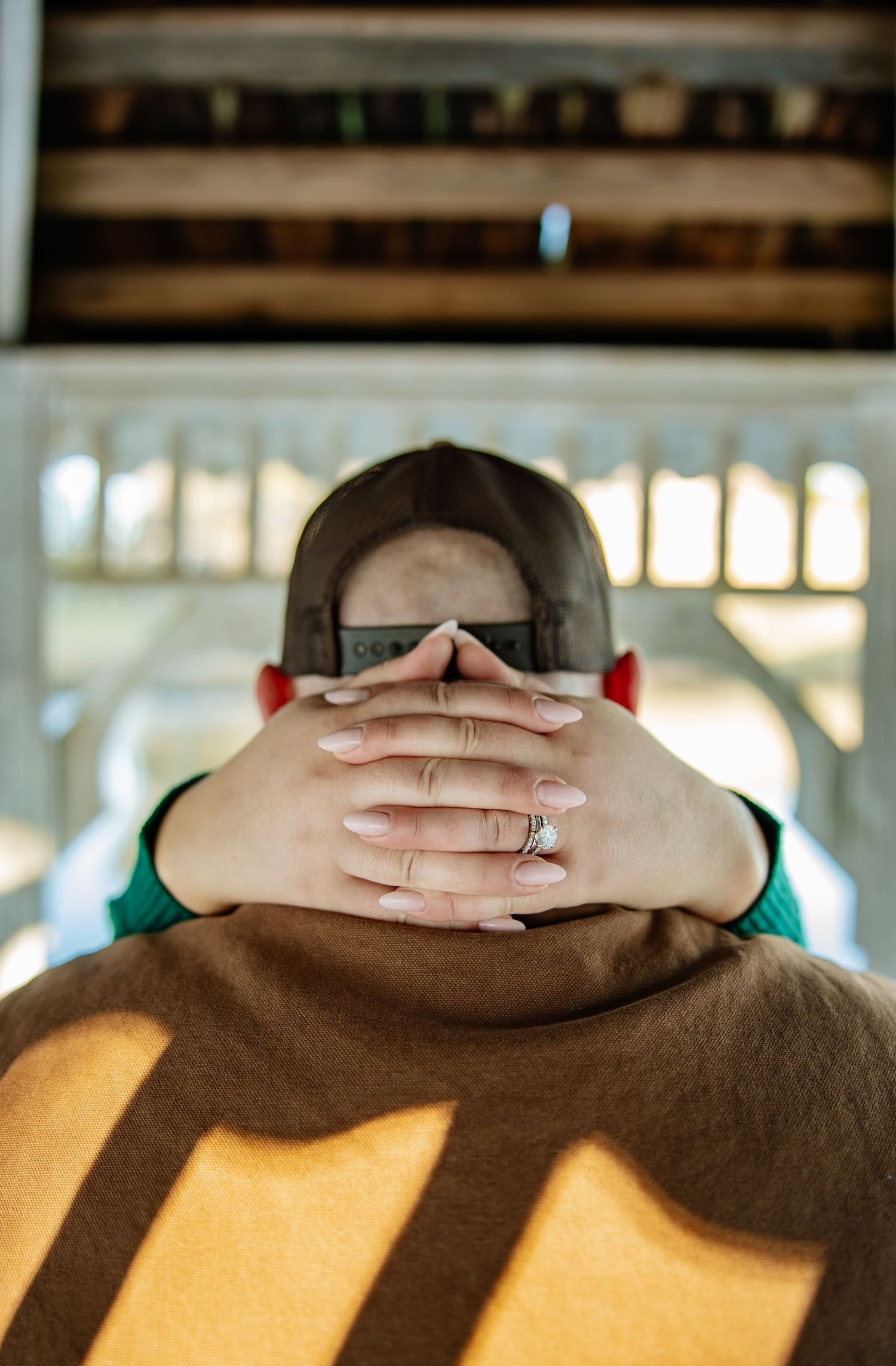 Hands clasped together resting on a brown surface in warm light.