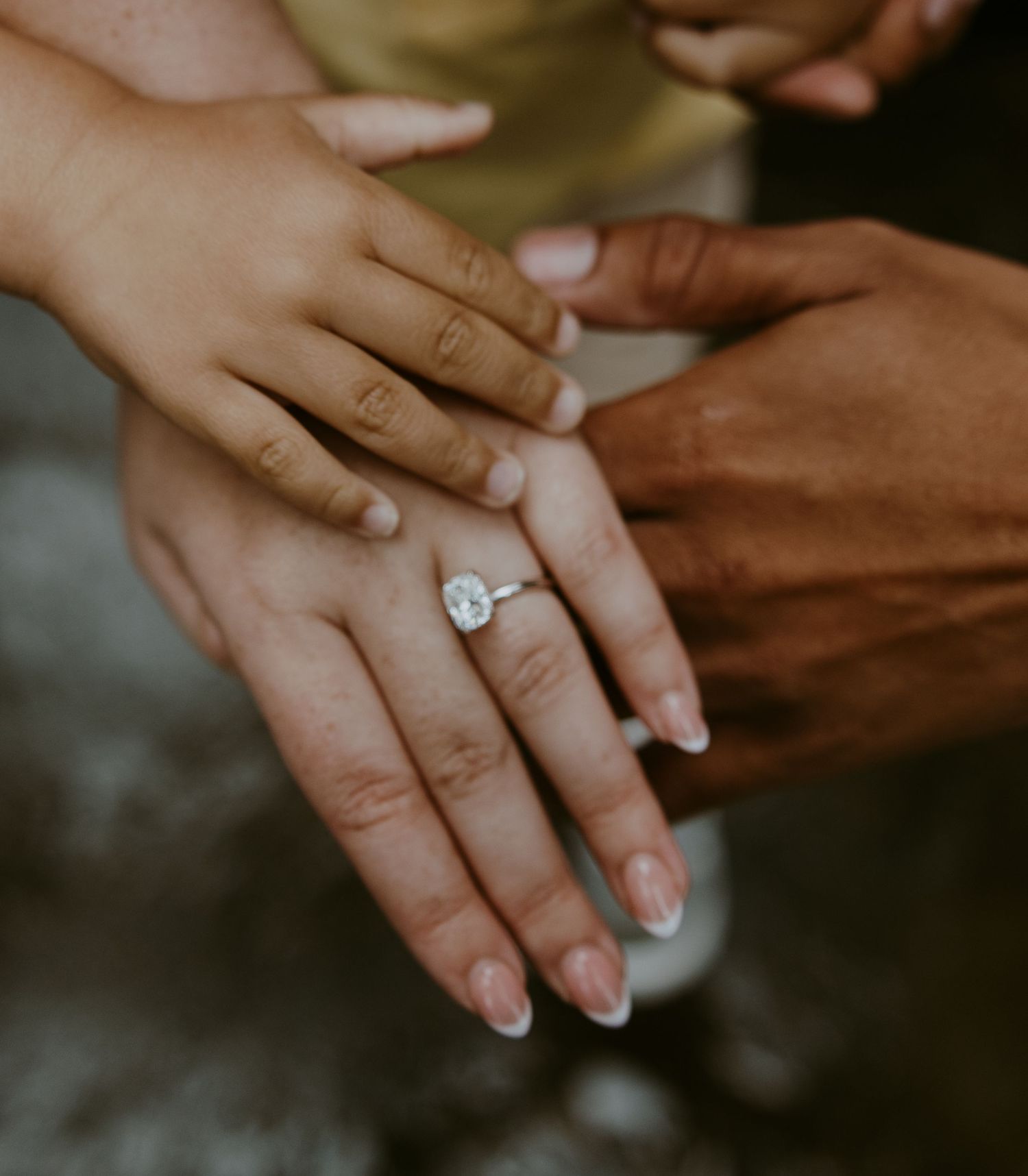 Close-up of hands displaying an engagement ring with soft natural lighting.