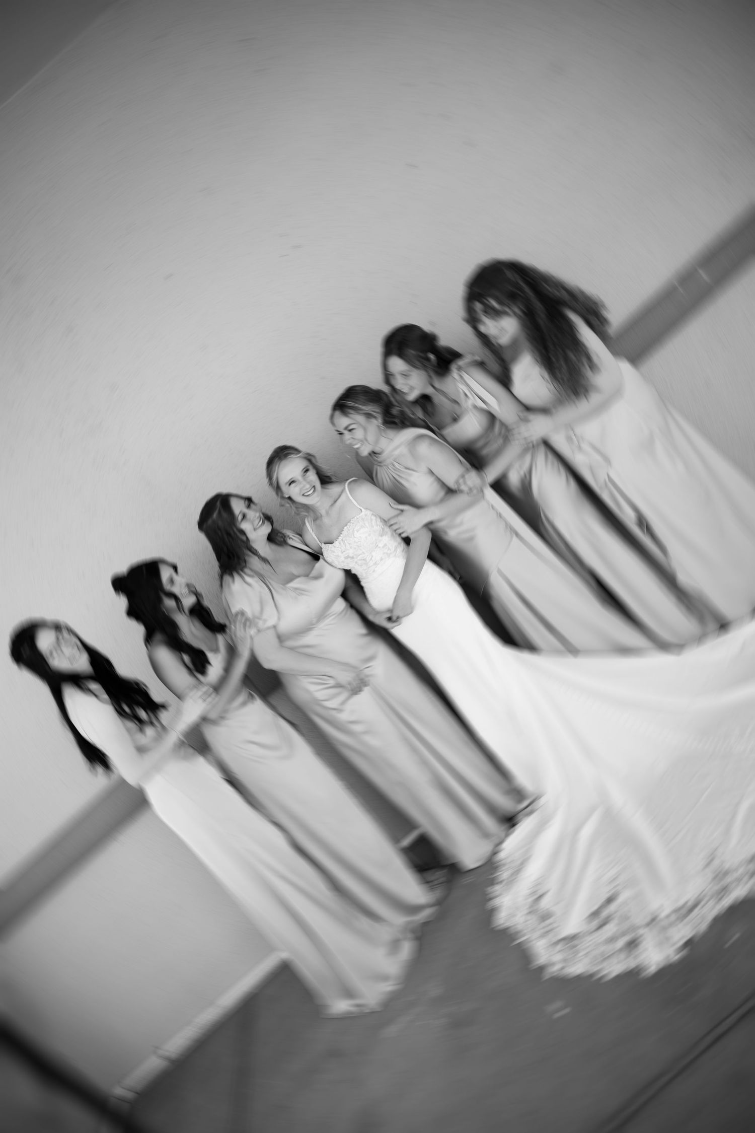 Black and white photo of a bride and bridesmaids in elegant gowns lined up together.