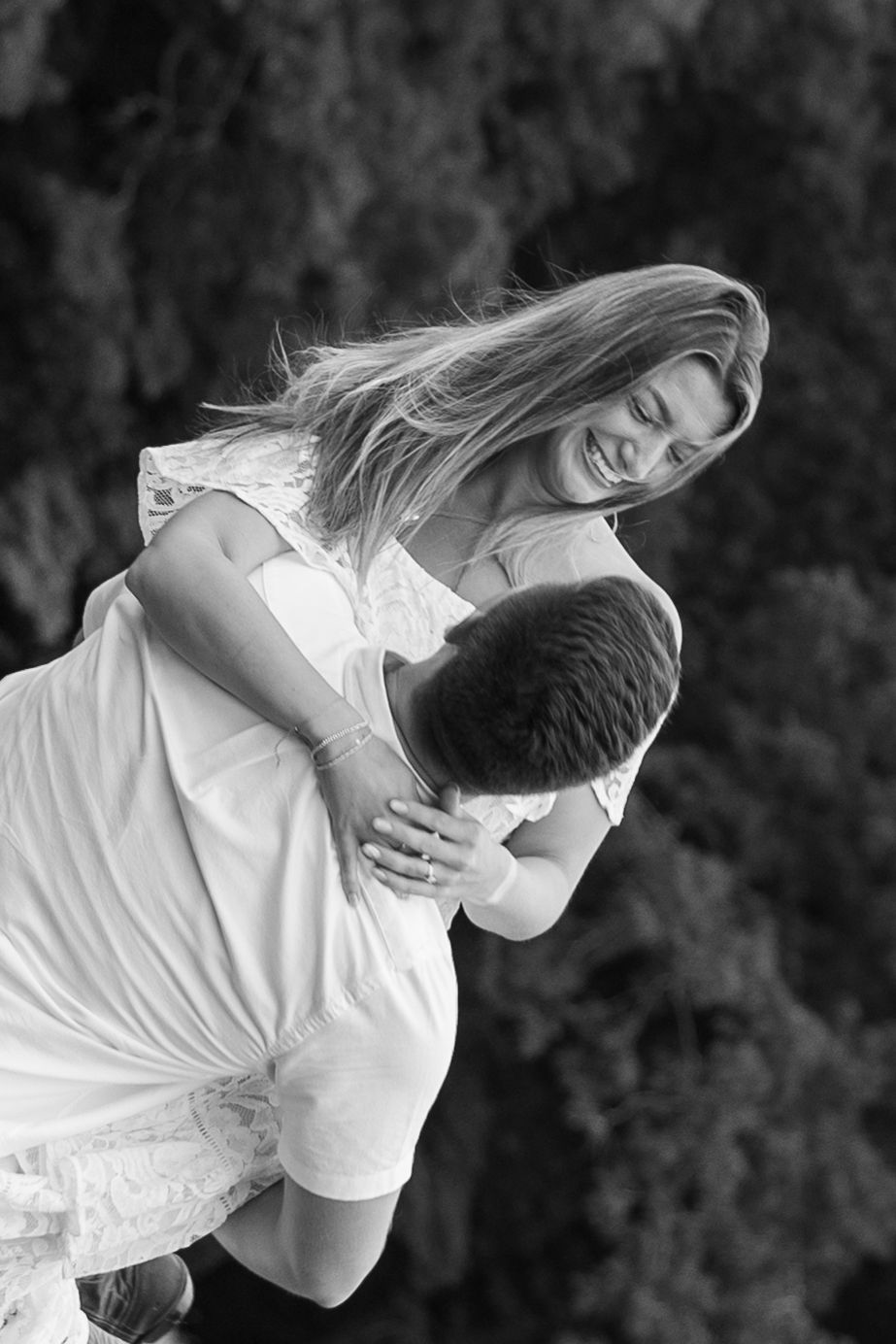 Black and white romantic photo series of a couple in white clothing embracing and dancing together outdoors.