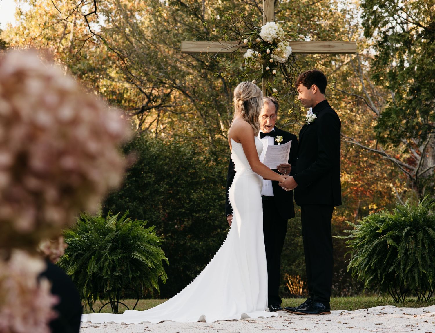 Outdoor wedding ceremony with couple standing at floral-decorated altar.
