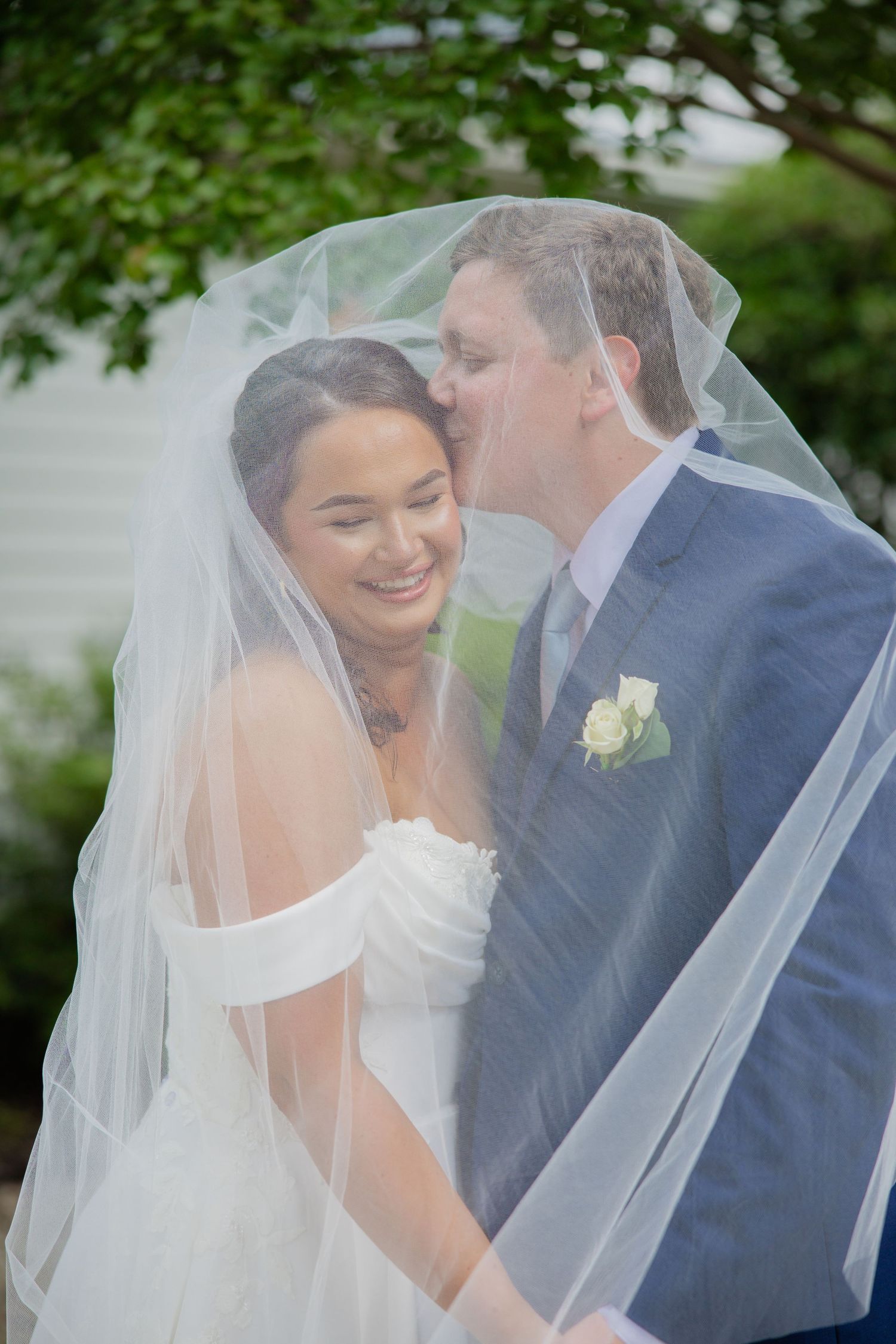 A romantic moment under a wedding veil with the couple sharing an intimate pose.
