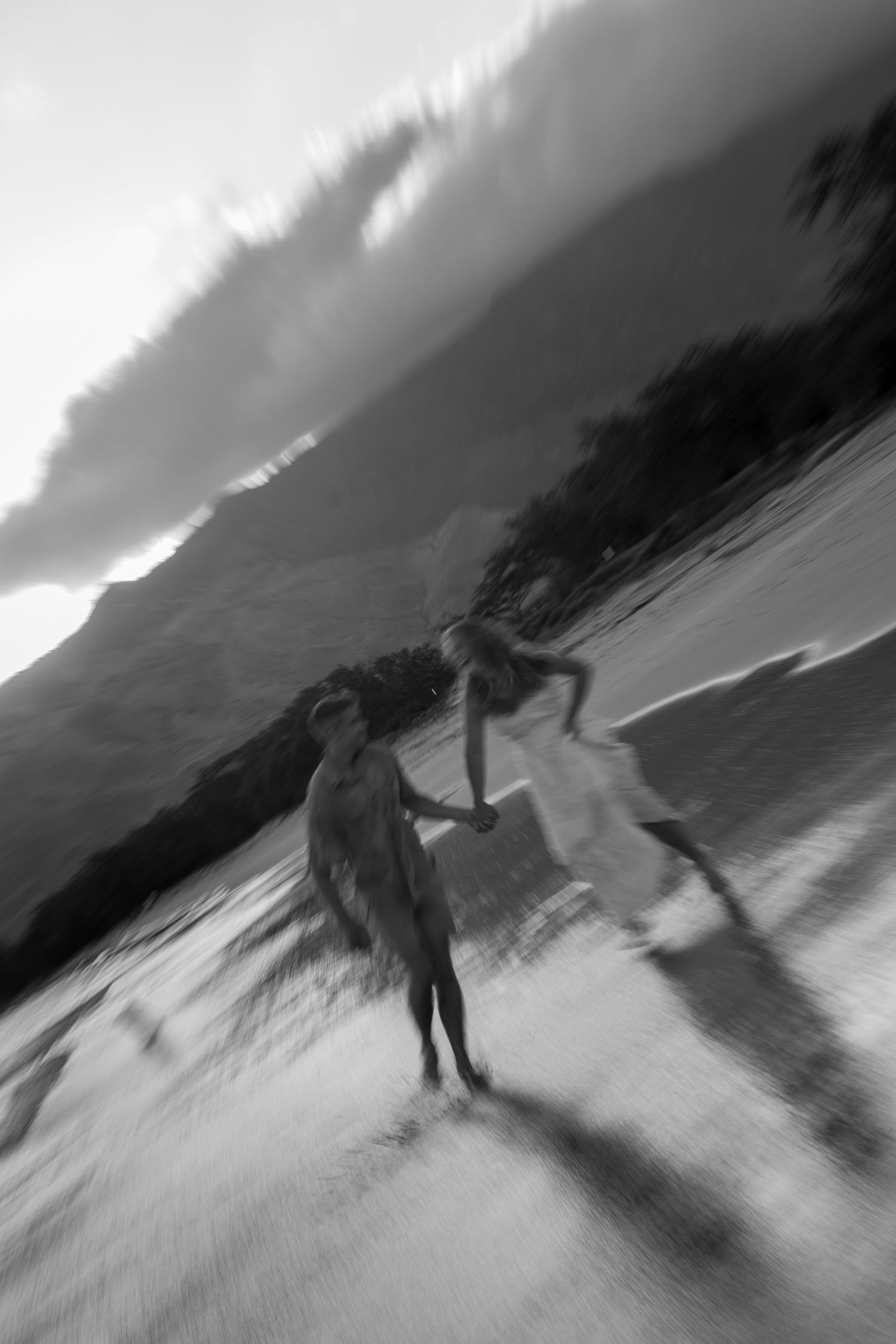 A dramatic black and white motion-blur photo of two people dancing on the beach.