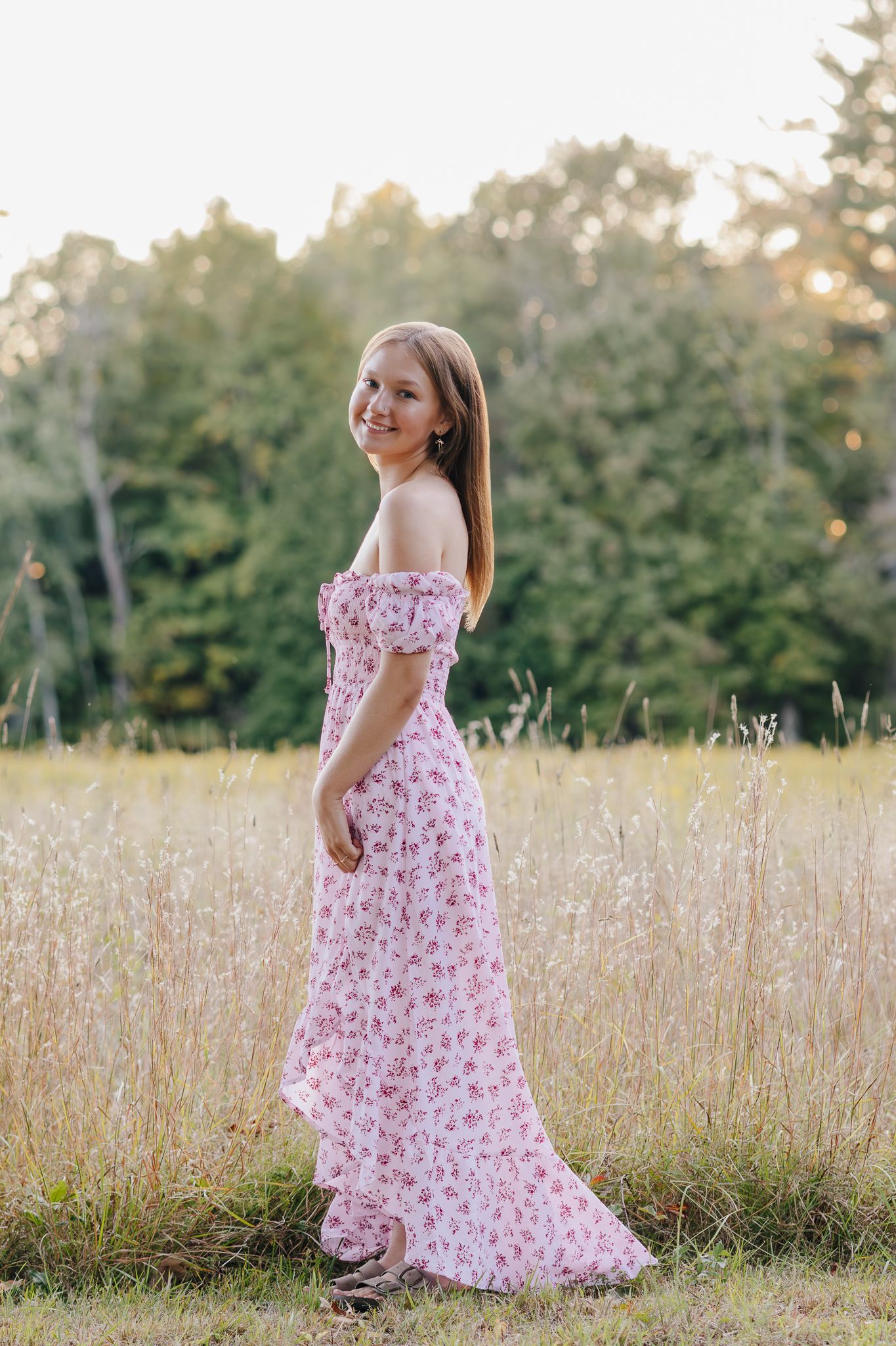 Senior portrait in a field with warm natural light.
