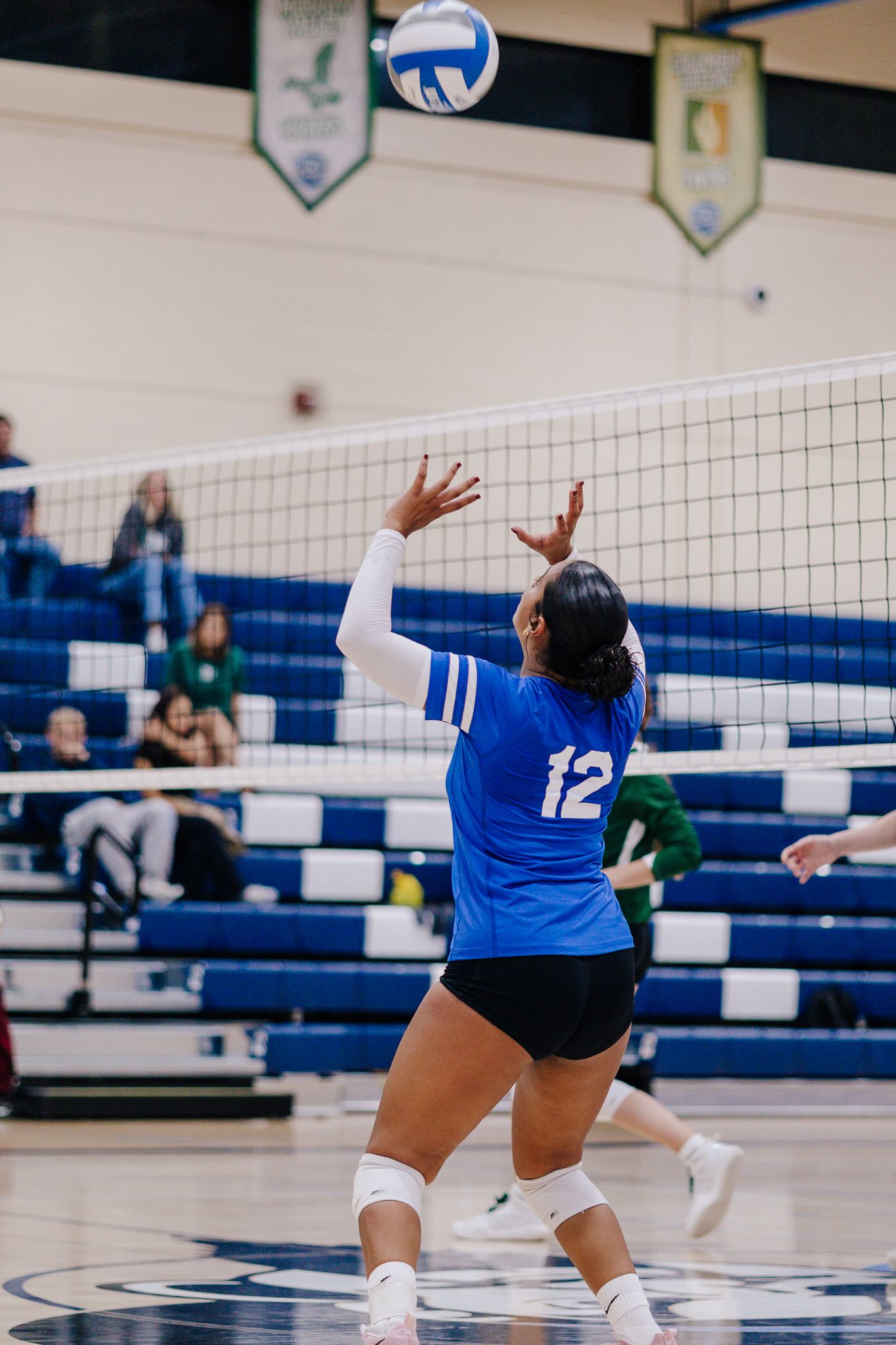 Volleyball player setting a ball during sports game.