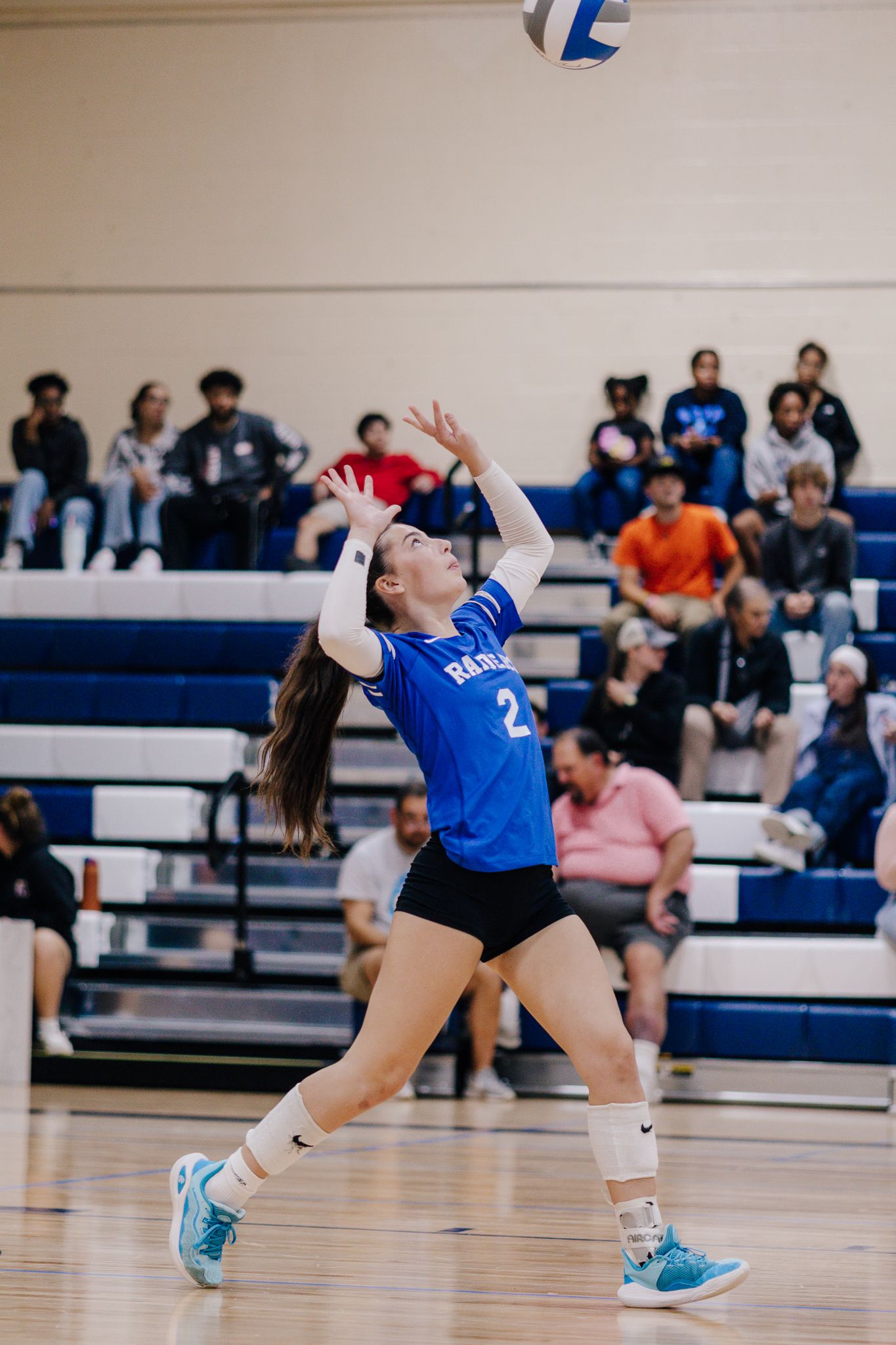 Volleyball player serving a ball during sports game.