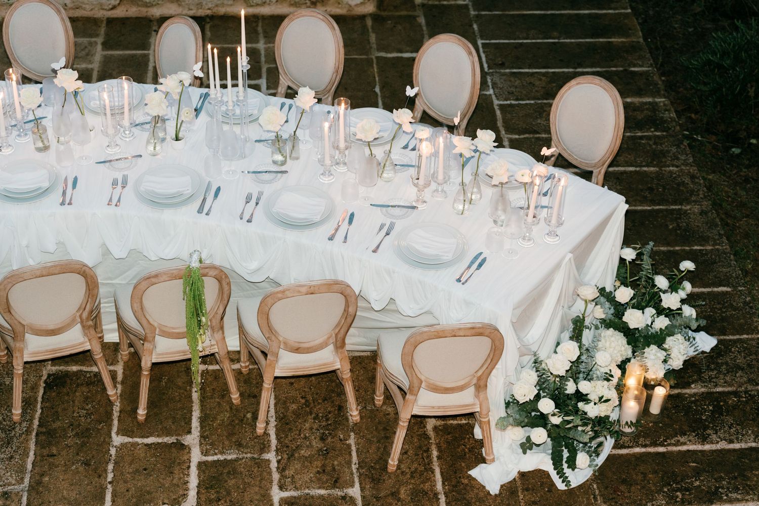 Elegant wedding reception table with white linens, gold chairs, candles, and floral arrangements. Puglia wedding photographer,