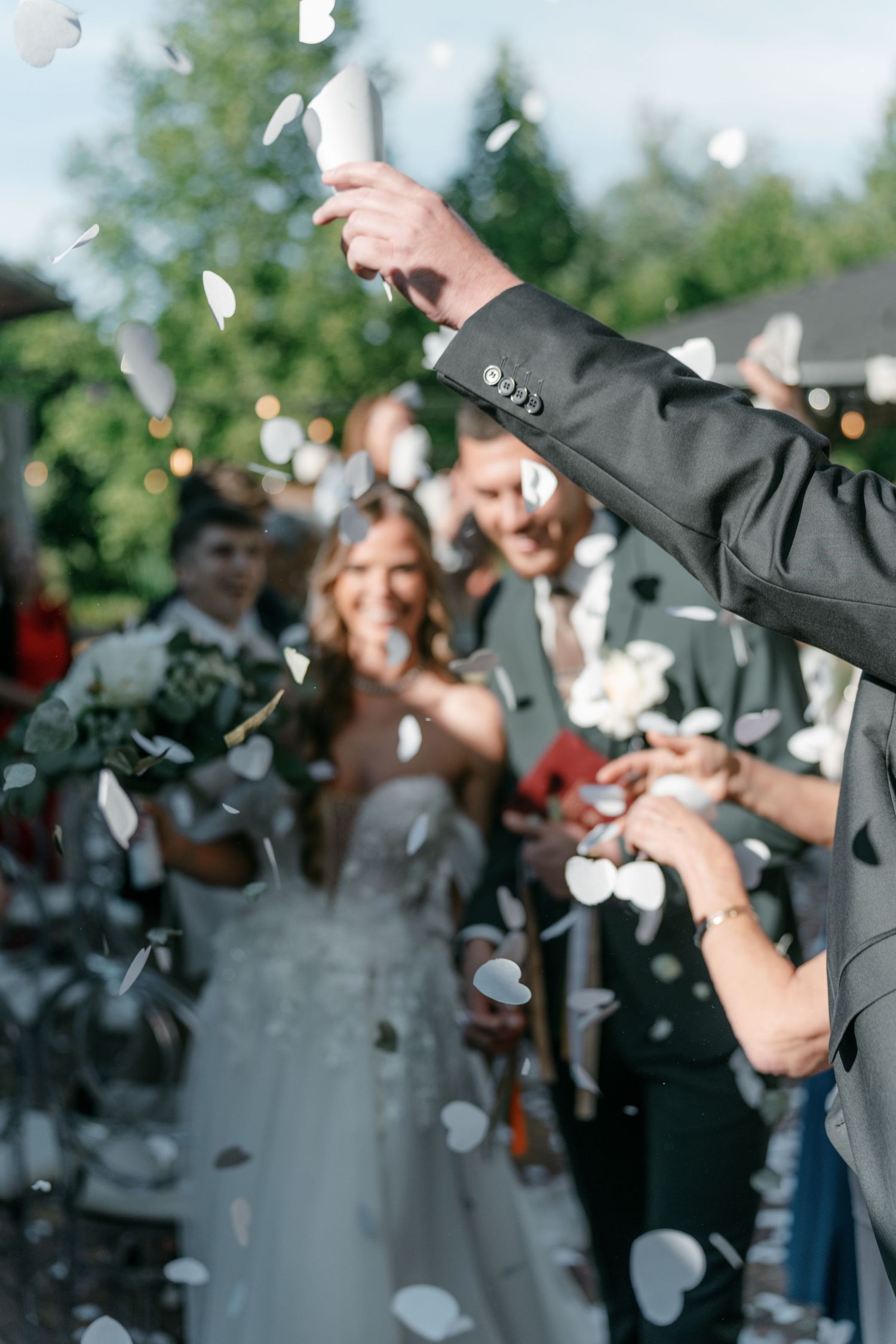 Wedding guests throwing white confetti petals as newlyweds walk through outdoor ceremony exit. Mallorca wedding photographer and filmmaker.