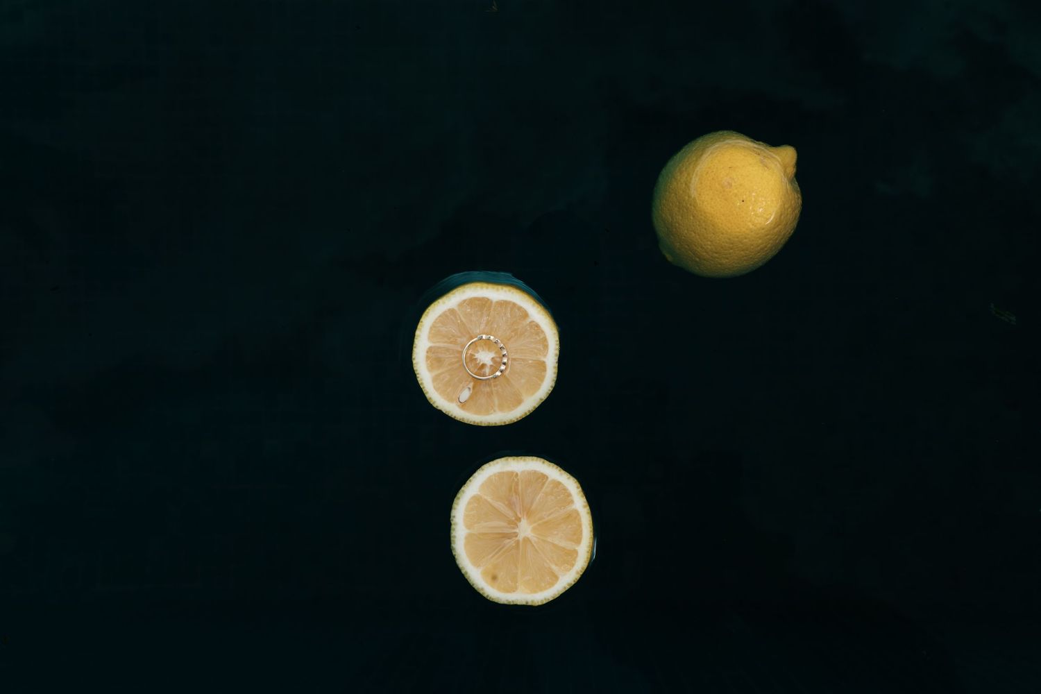 Two lemon slices and a whole lemon arranged on a dark background. Mallorca wedding photographer, filmmaker